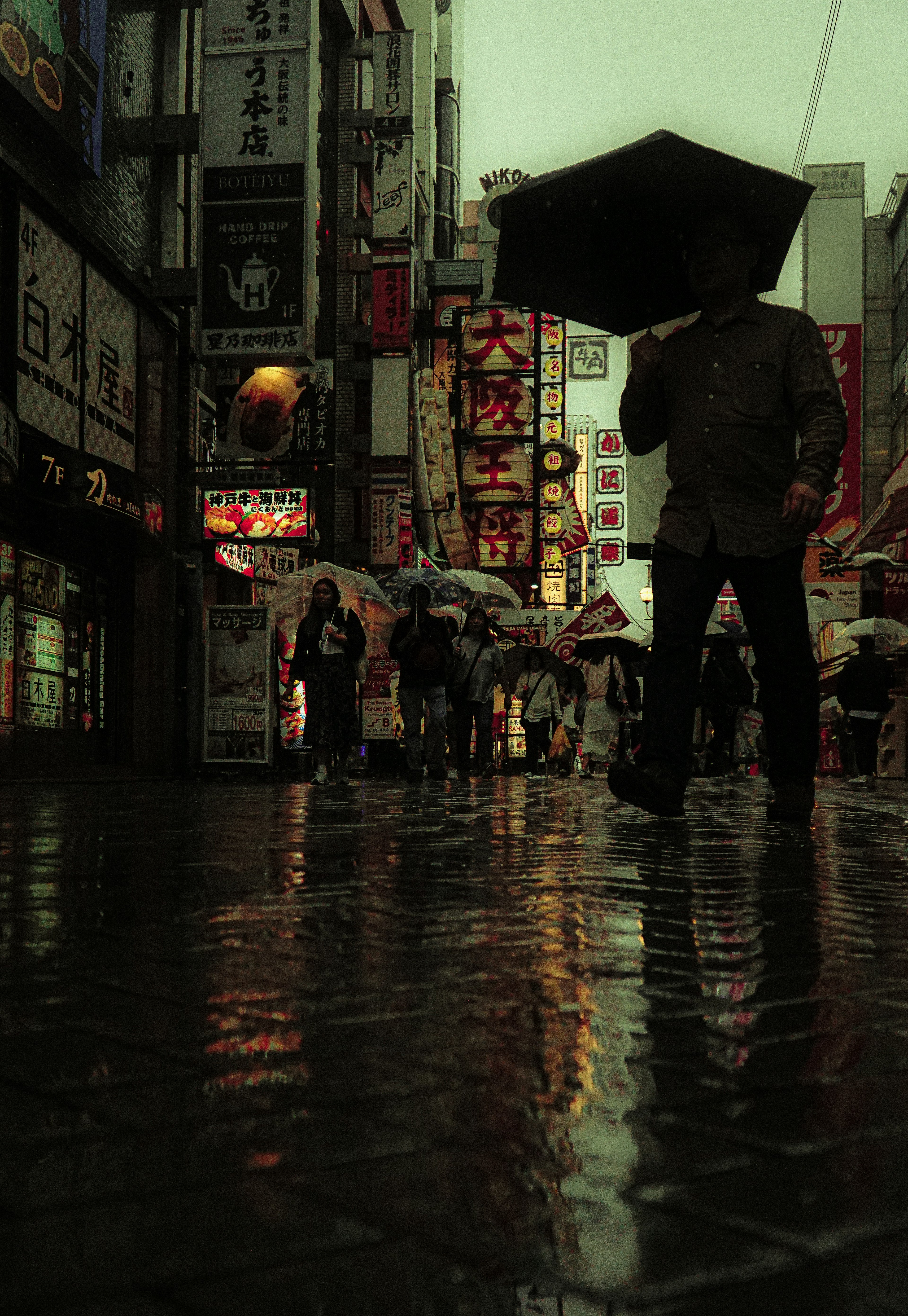 手持雨傘的人在雨中街道上的反射