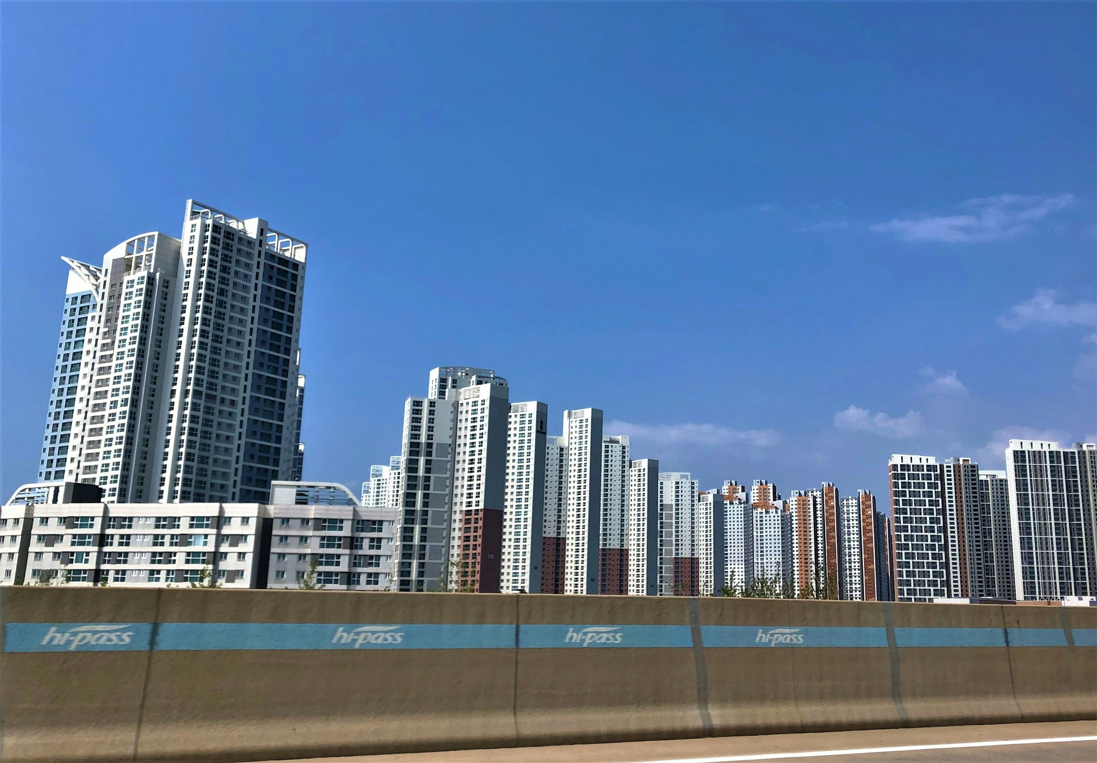 Edificios de gran altura alineados bajo un cielo azul con una carretera en primer plano