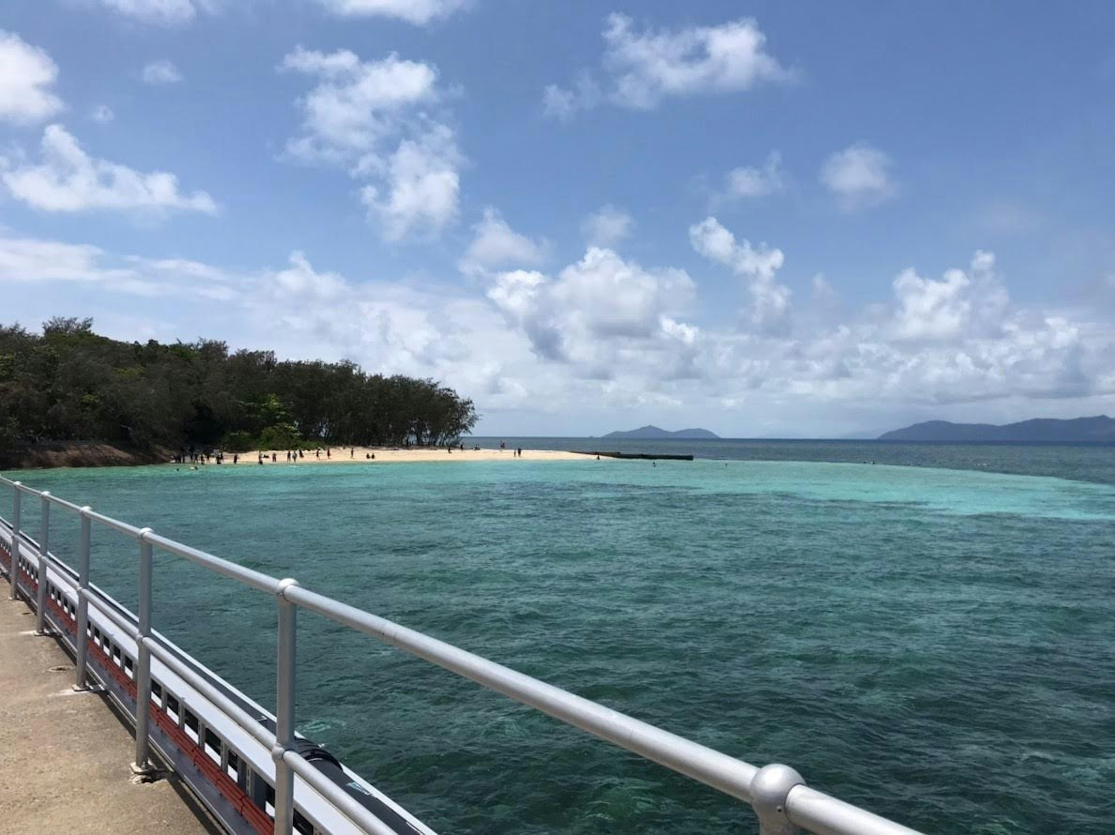 Vista escénica de un océano azul con una playa de arena e islas distantes