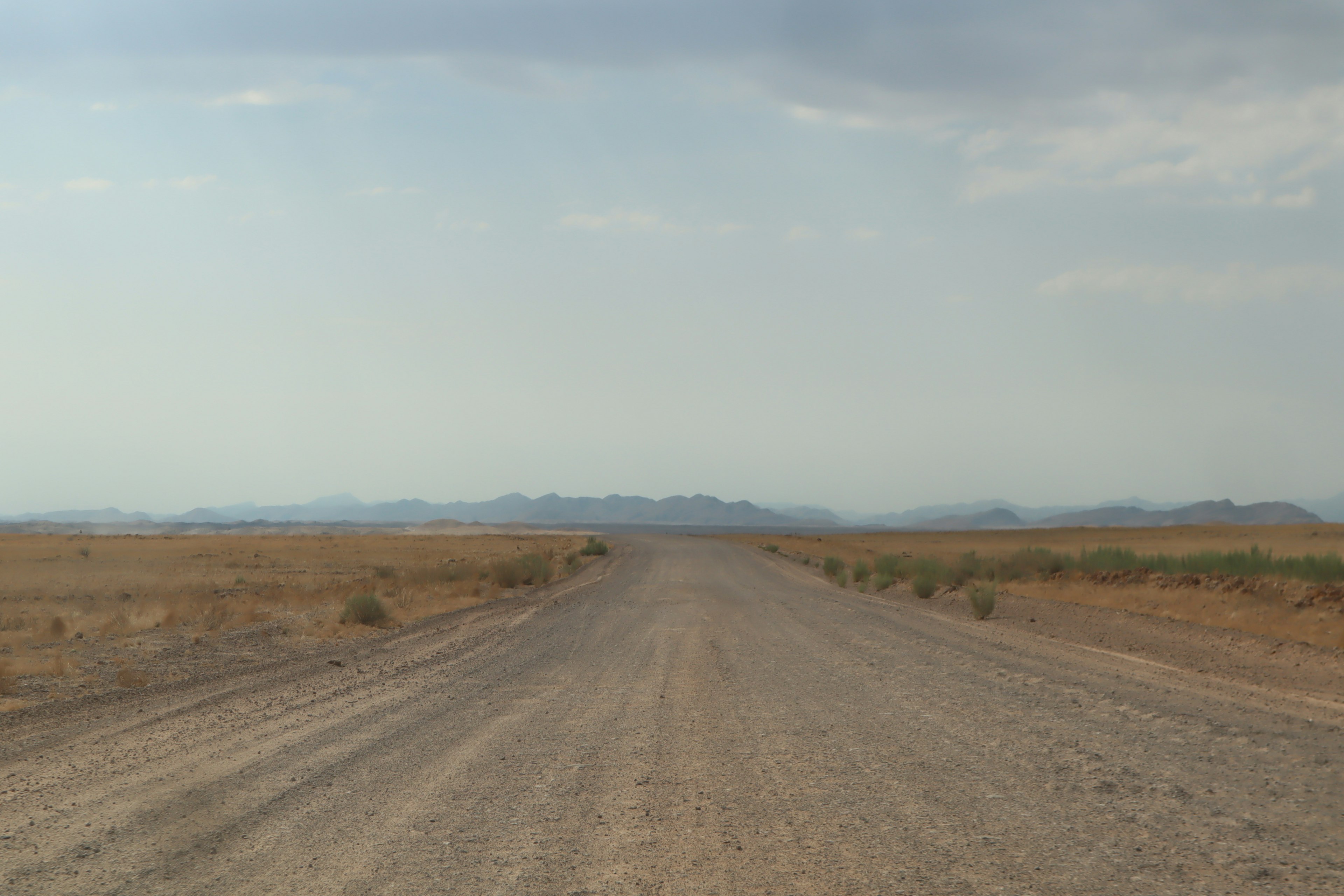 Unbefestigte Straße, die sich durch eine trockene Landschaft erstreckt