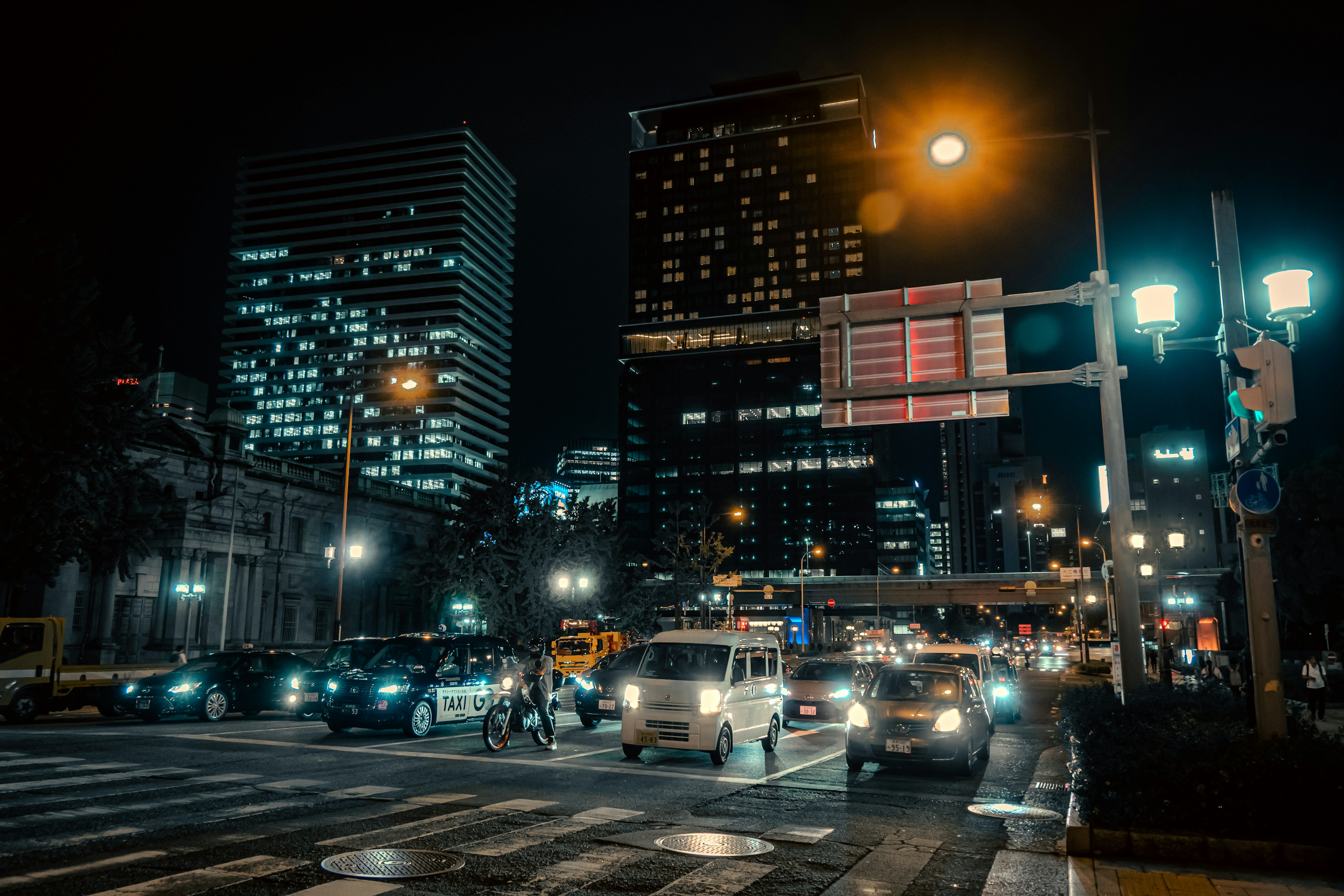 夜の都市風景と明るいビル群、交通信号と街灯が映える交差点