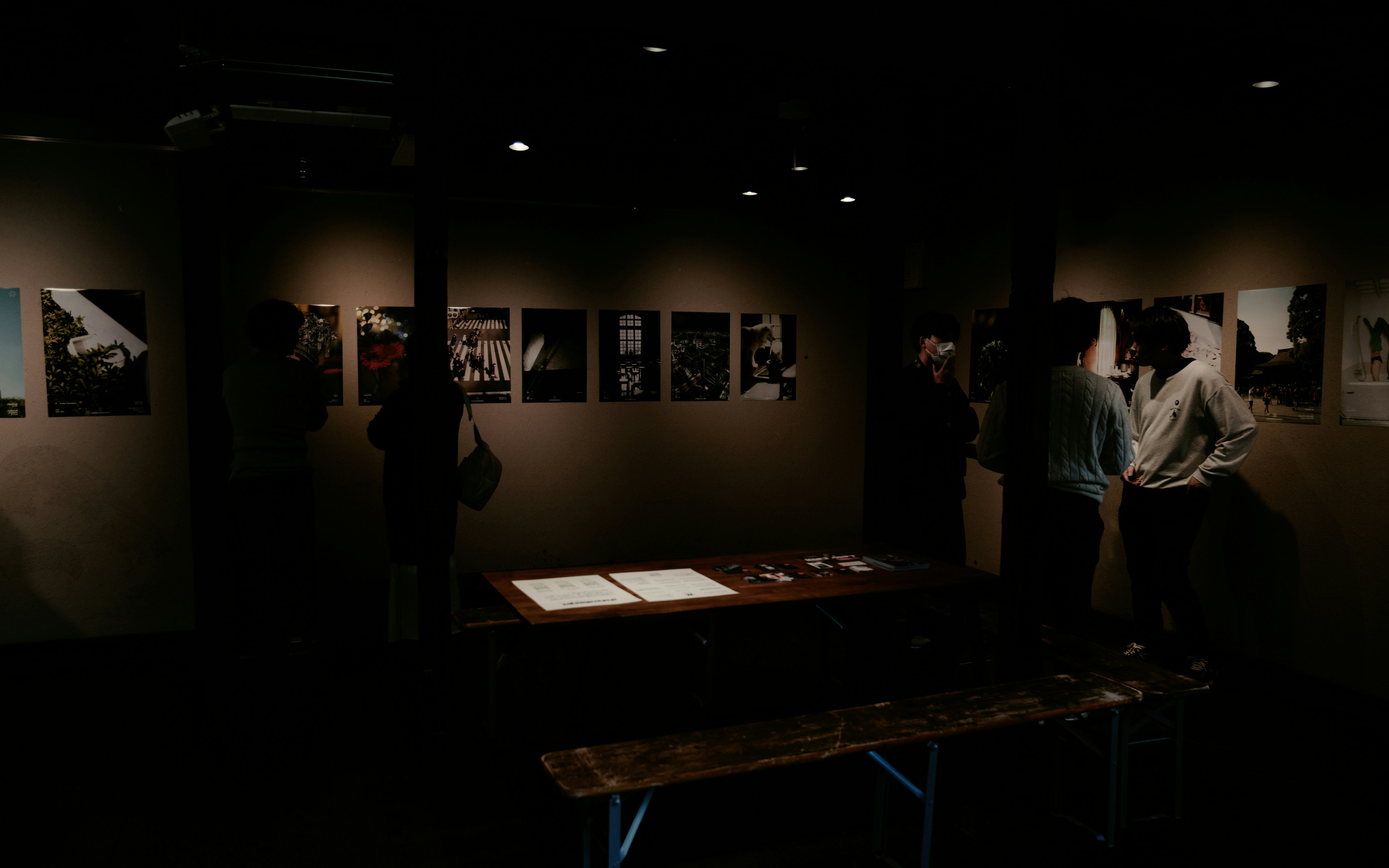 Galeri redup yang gelap menampilkan pameran foto dan pengunjung