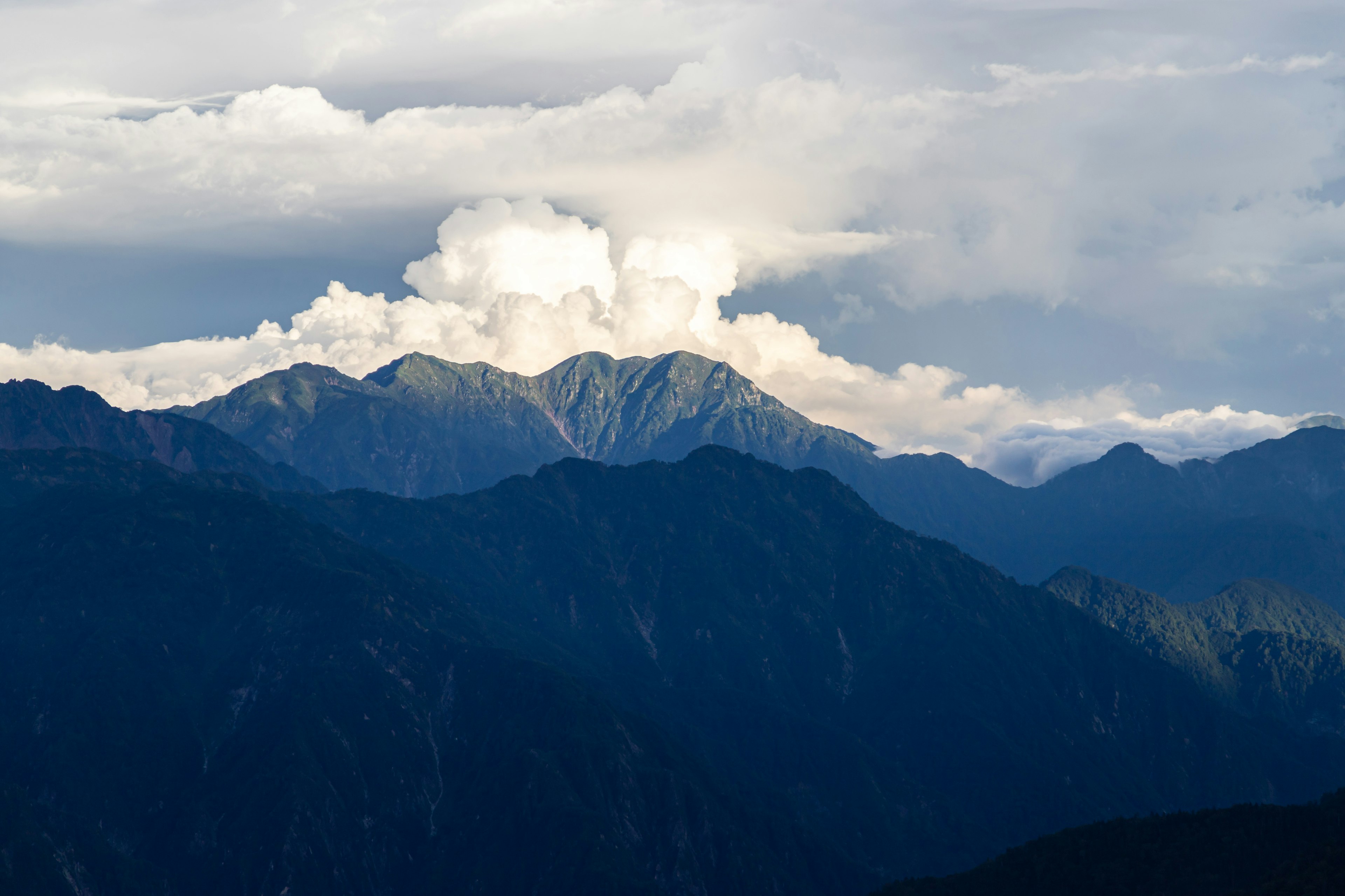 Paesaggio montano drammatico con nuvole e tonalità di blu