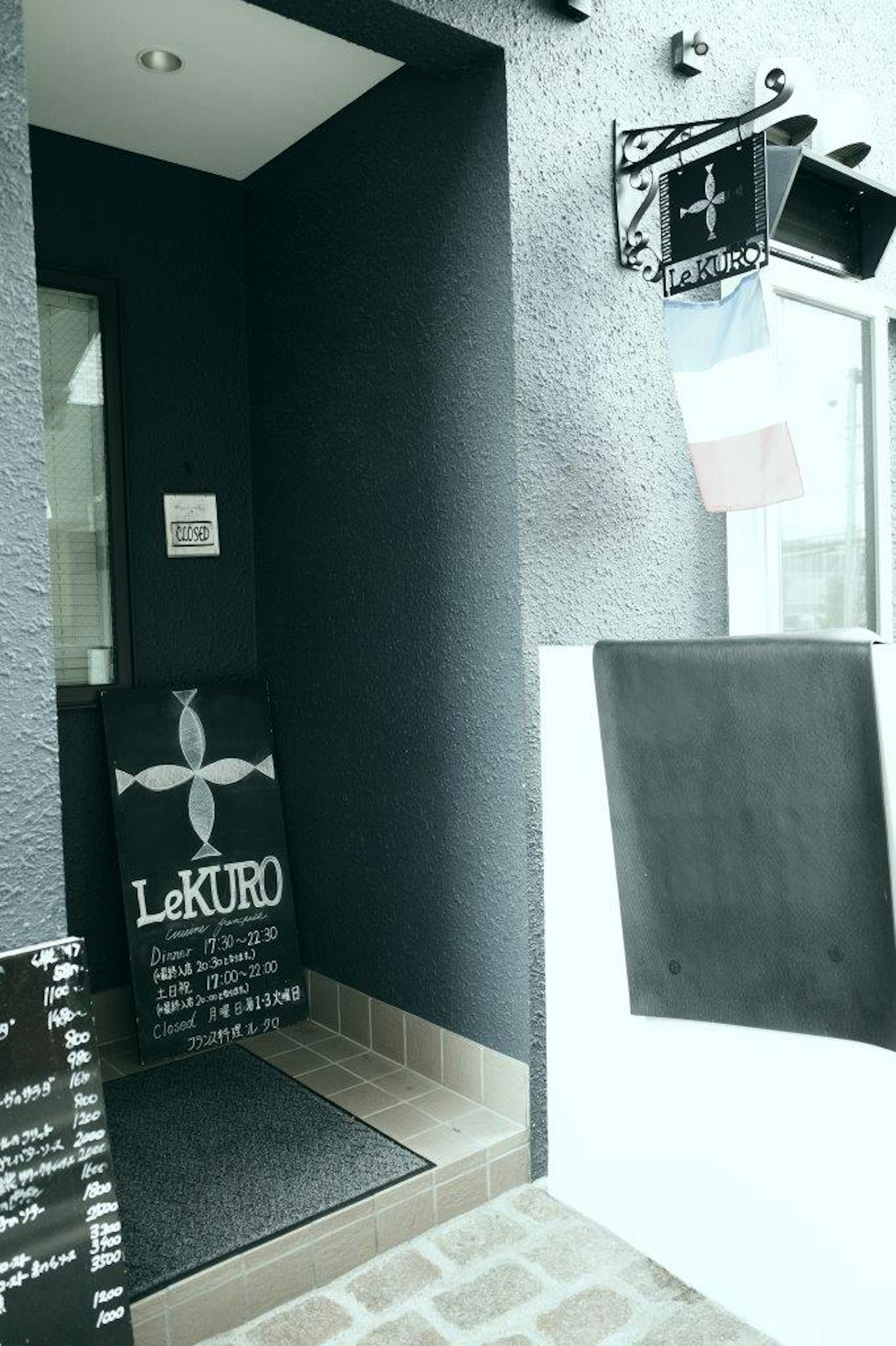 Entrance with black wall featuring LeKURO sign and French flag