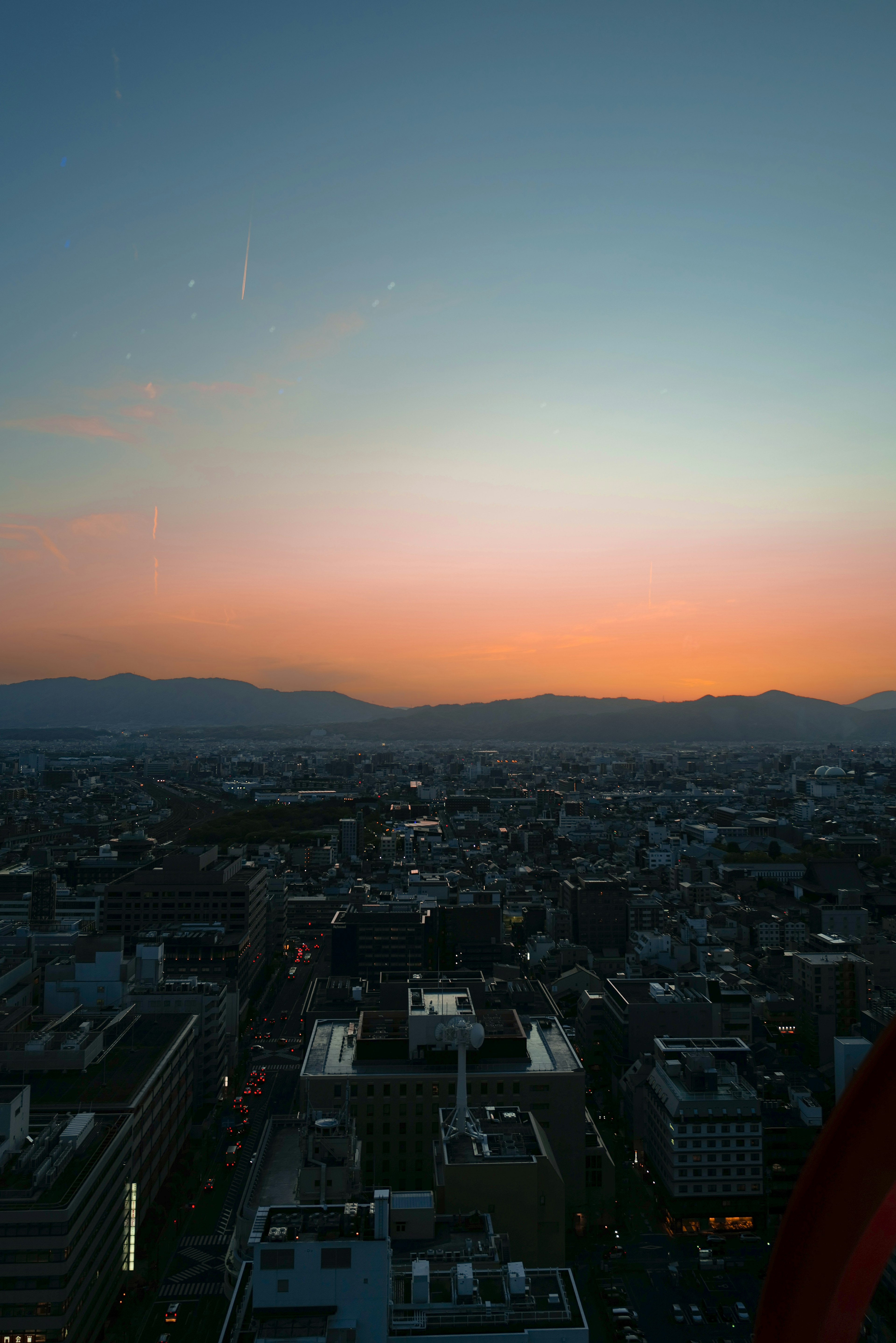 Cityscape at sunset with colorful sky and distant mountains