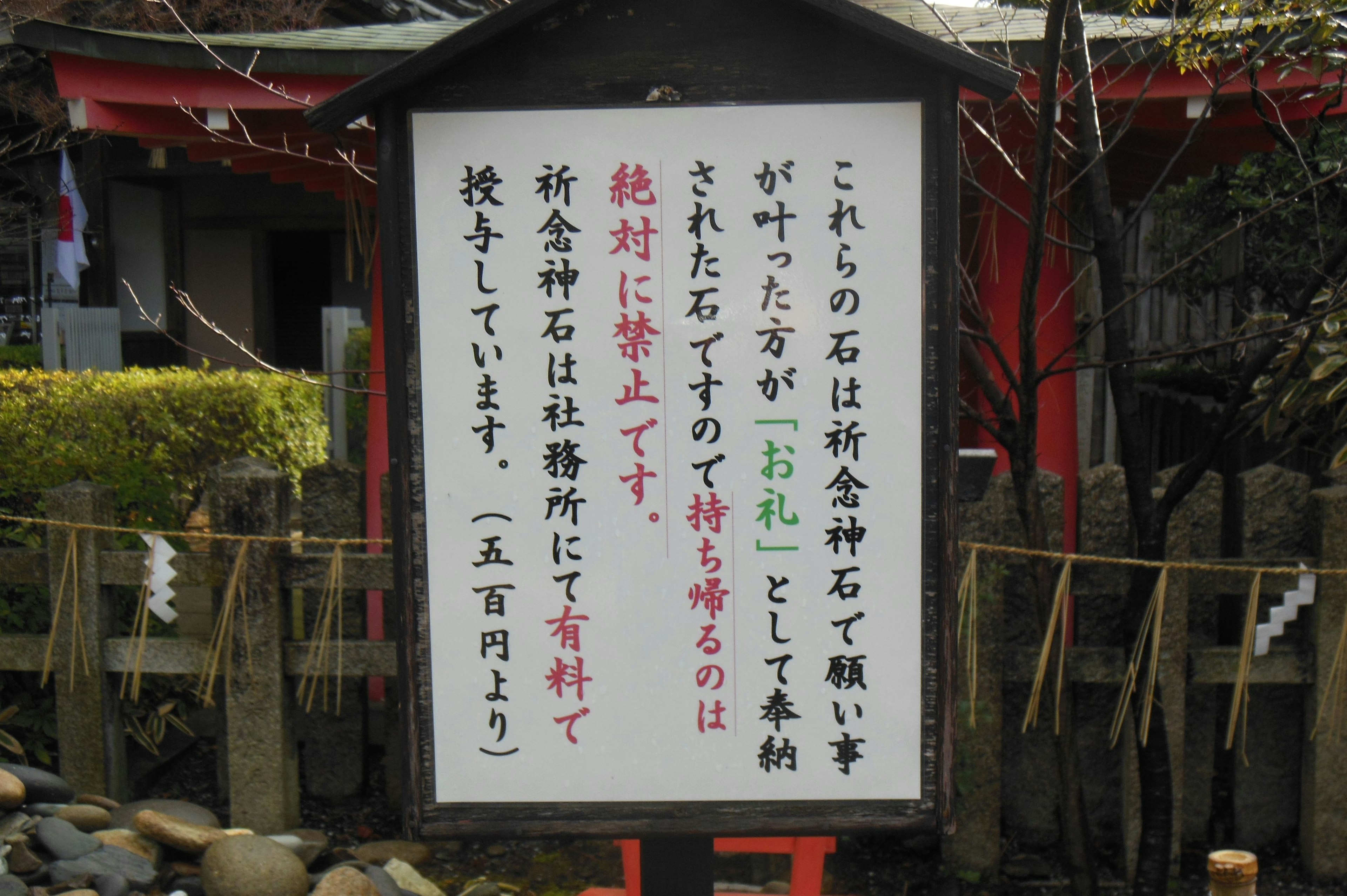 この石は神社の神聖な石であり、触れてはいけないと警告する看板