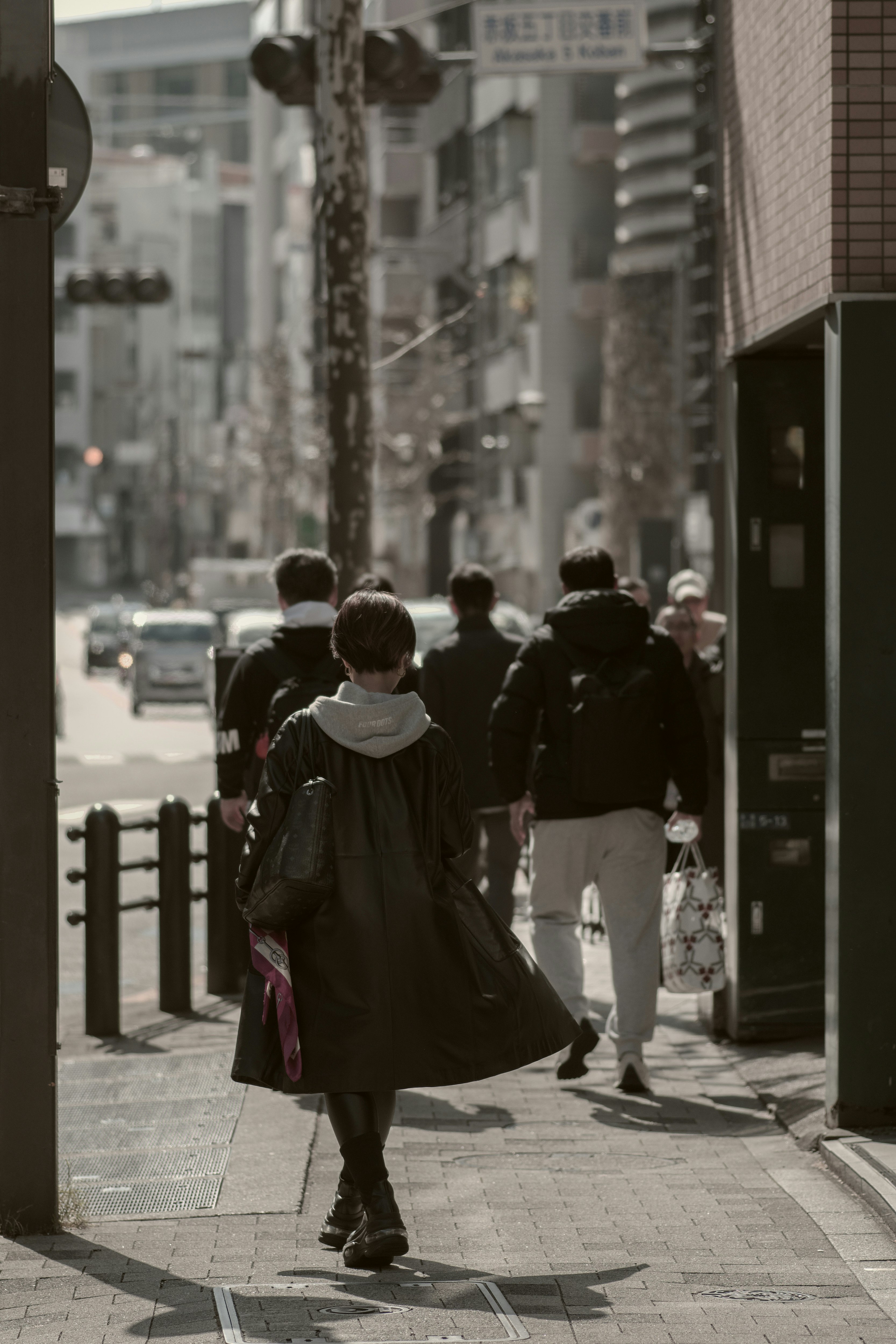 검은 코트를 입은 여성이 배경의 보행자들과 함께 걷고 있다