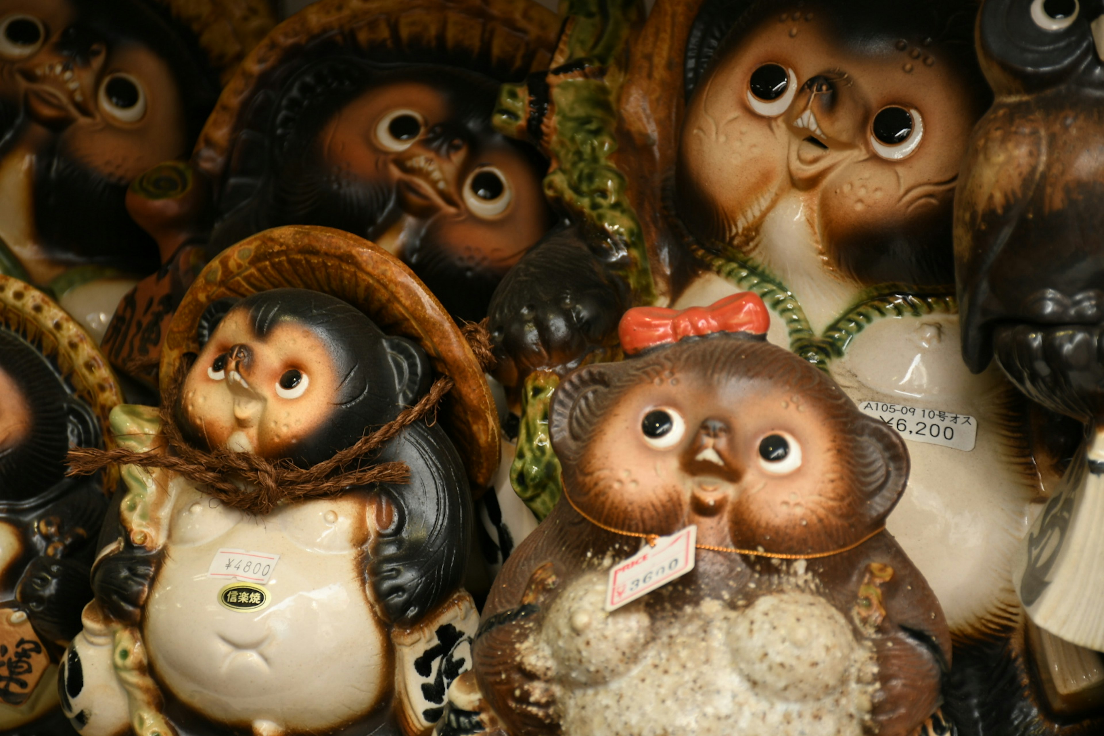 A collection of ceramic tanuki figurines featuring colorful hats and outfits