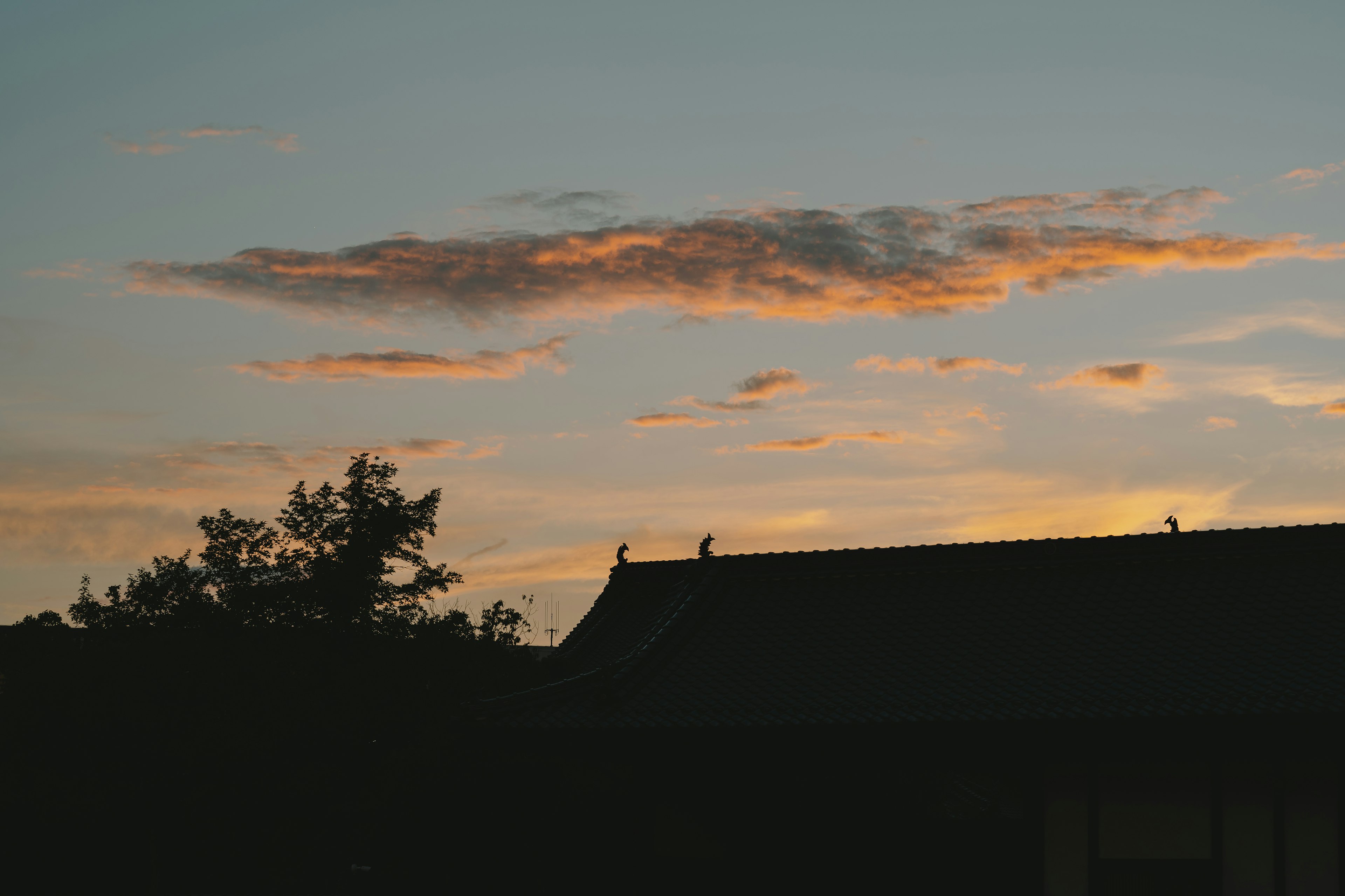 Silhouette of a roof against a colorful sunset sky