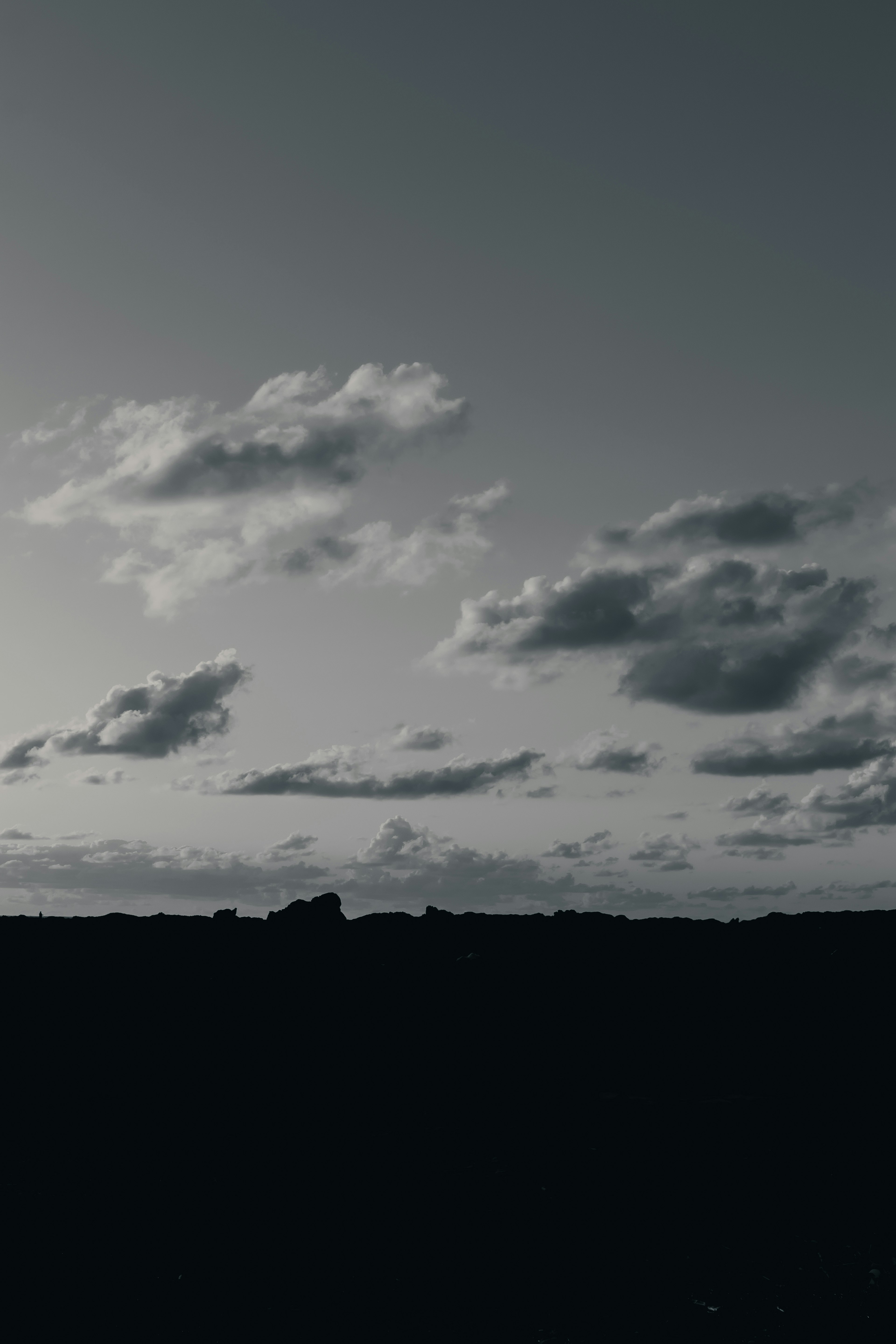 Nuages éparpillés sur un horizon sombre sous un ciel tamisé