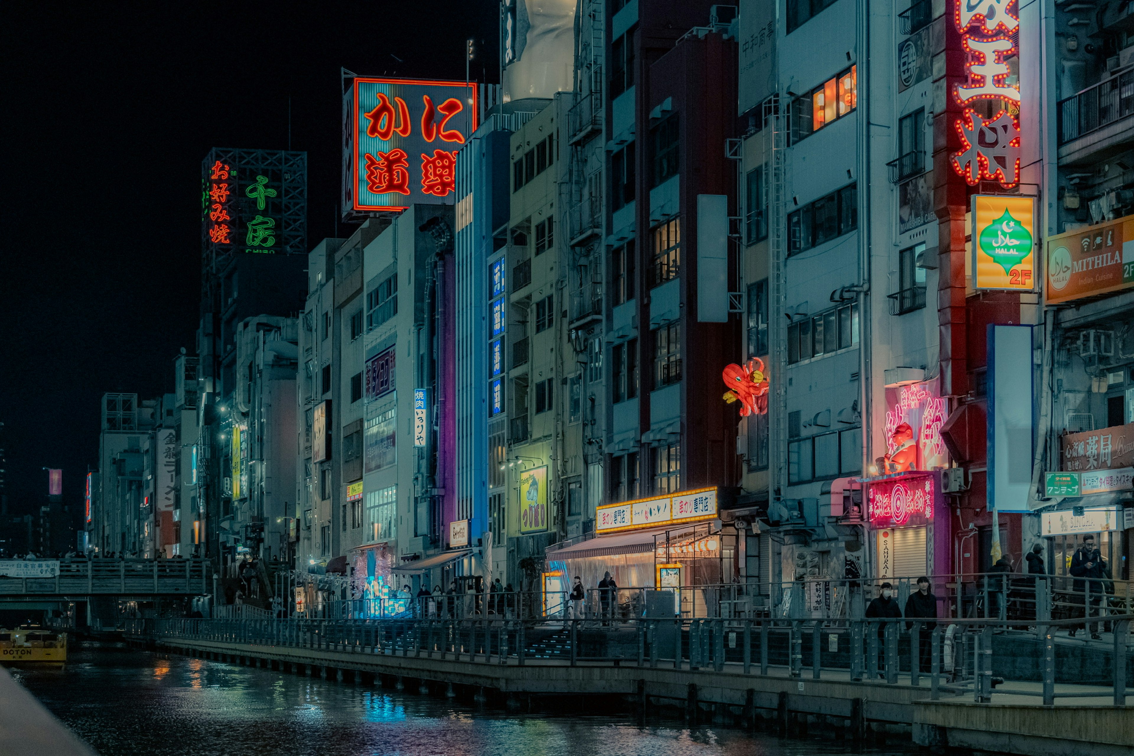 Night cityscape with glowing neon signs and buildings along a river