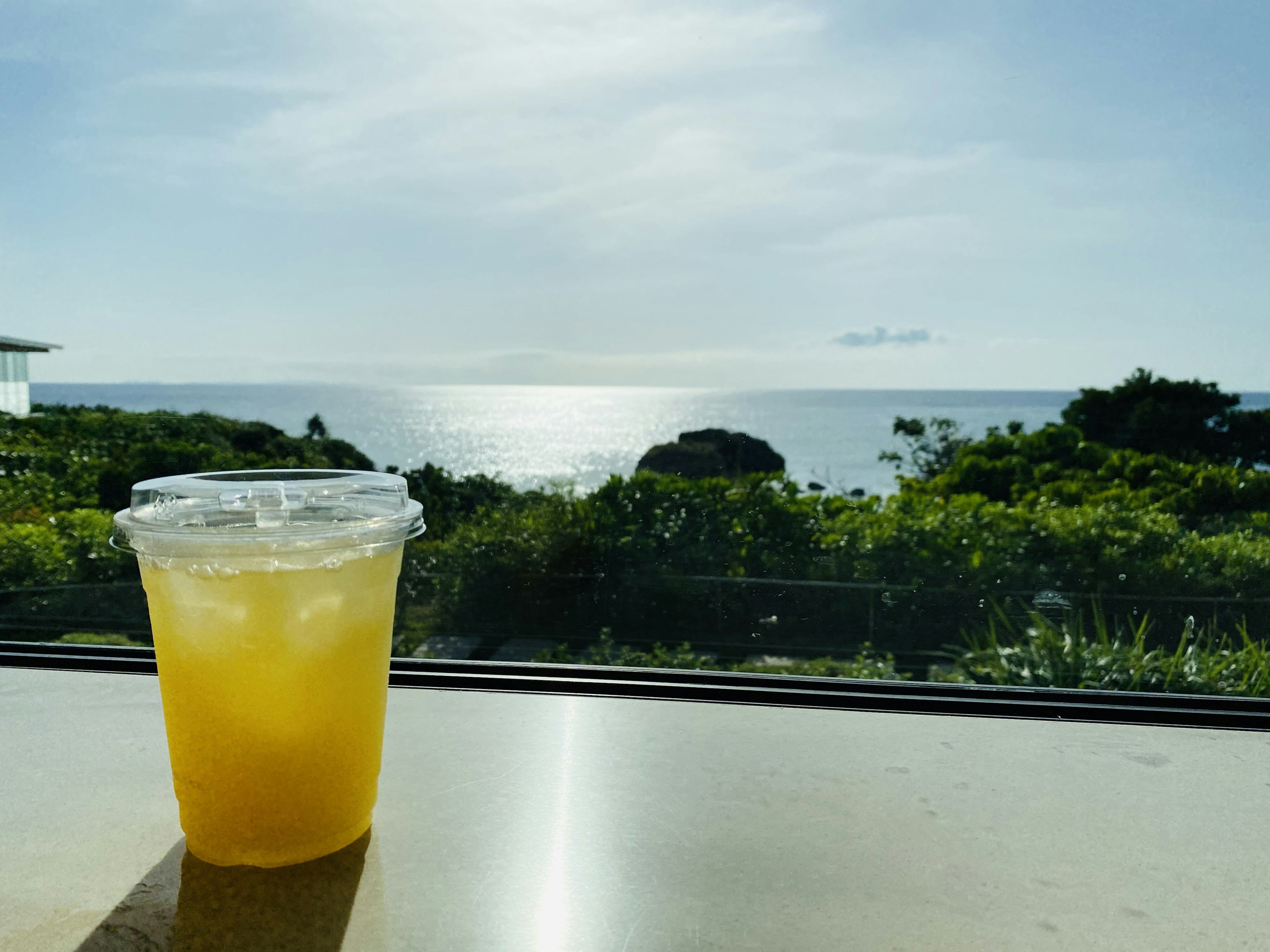 Un vaso de bebida naranja con vista al océano de fondo