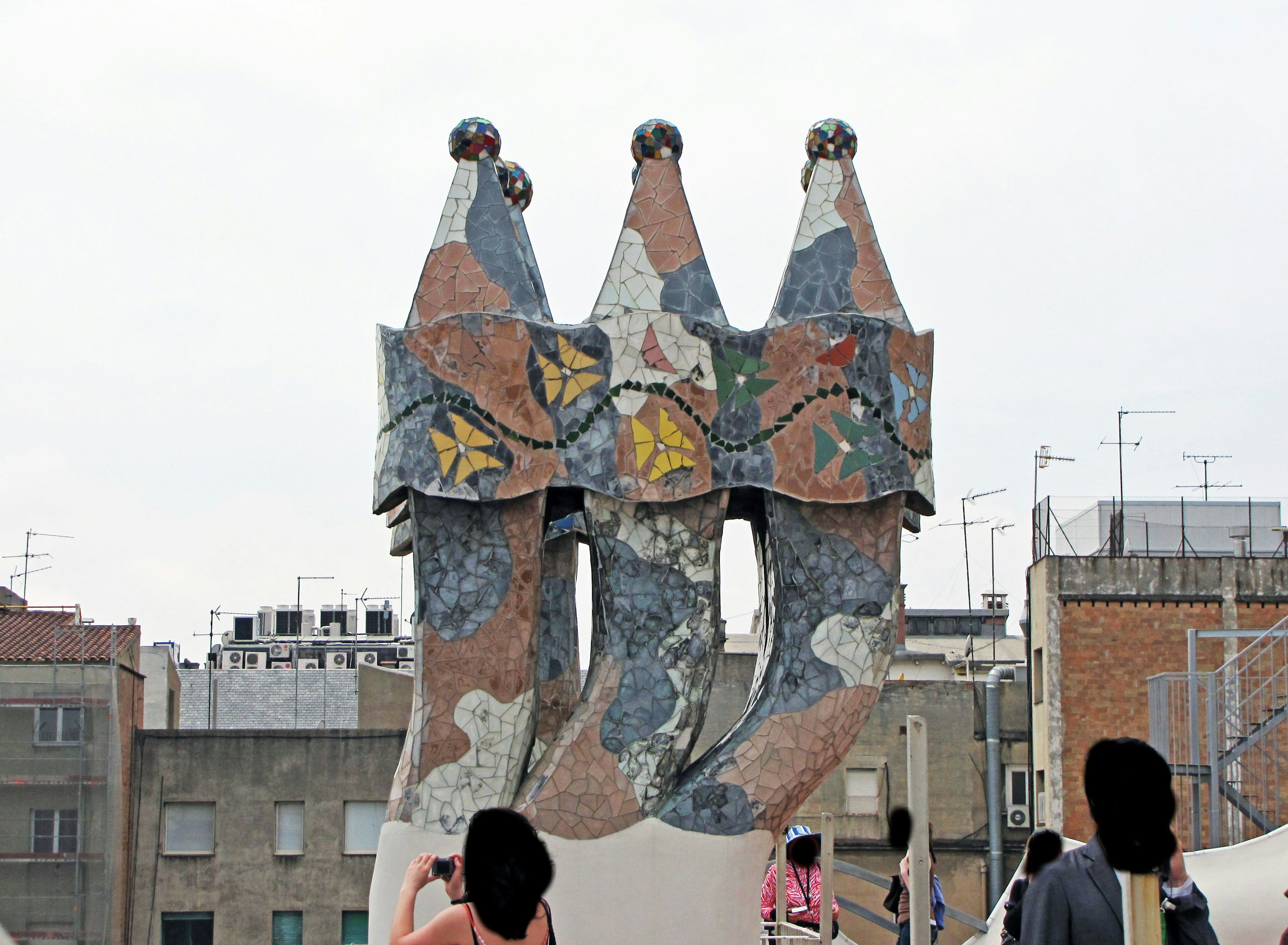 Unique sculpture of three figures on the rooftop of Casa Mila featuring colorful mosaic patterns