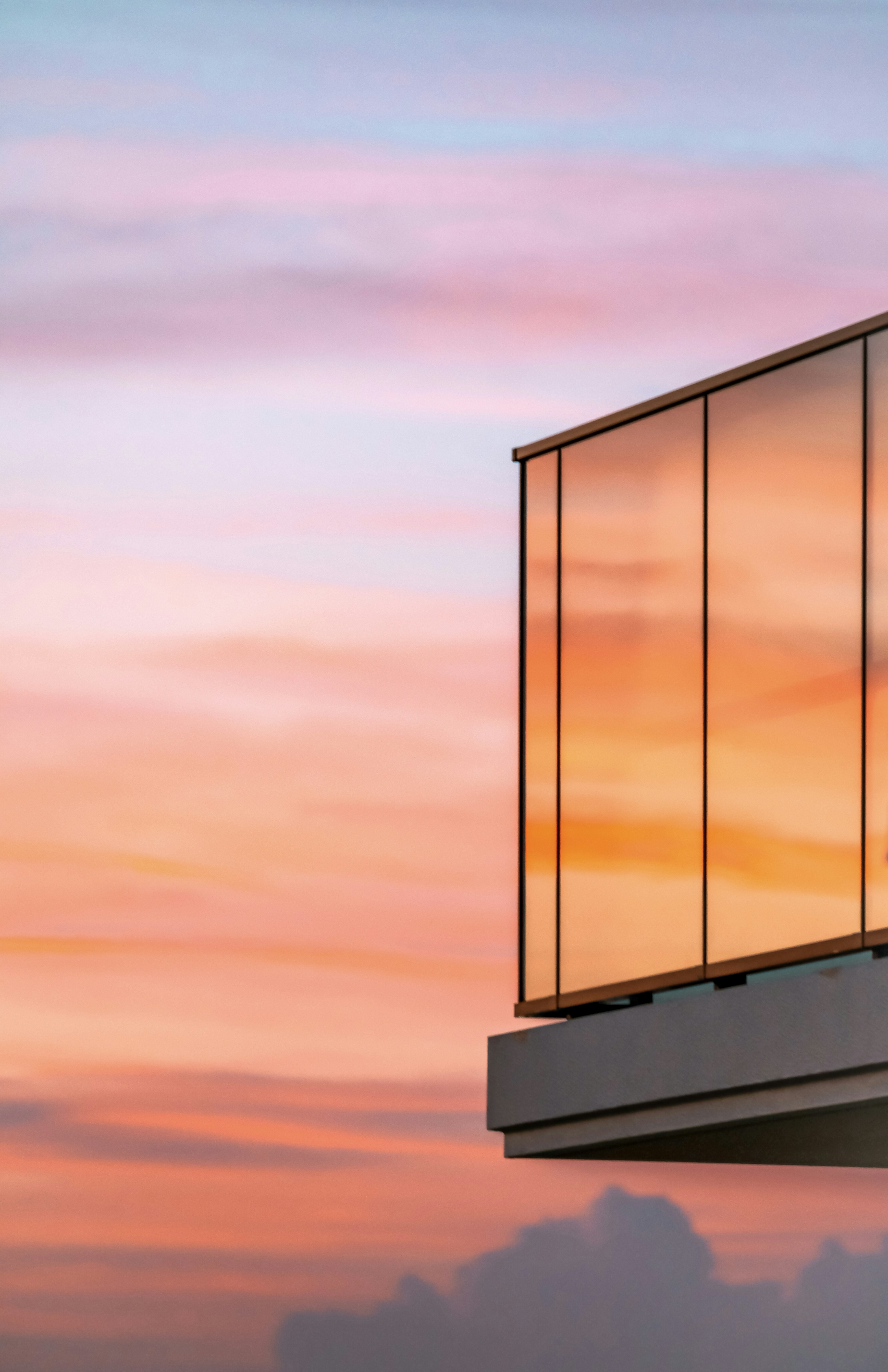 Part of a glass balcony against a sunset sky