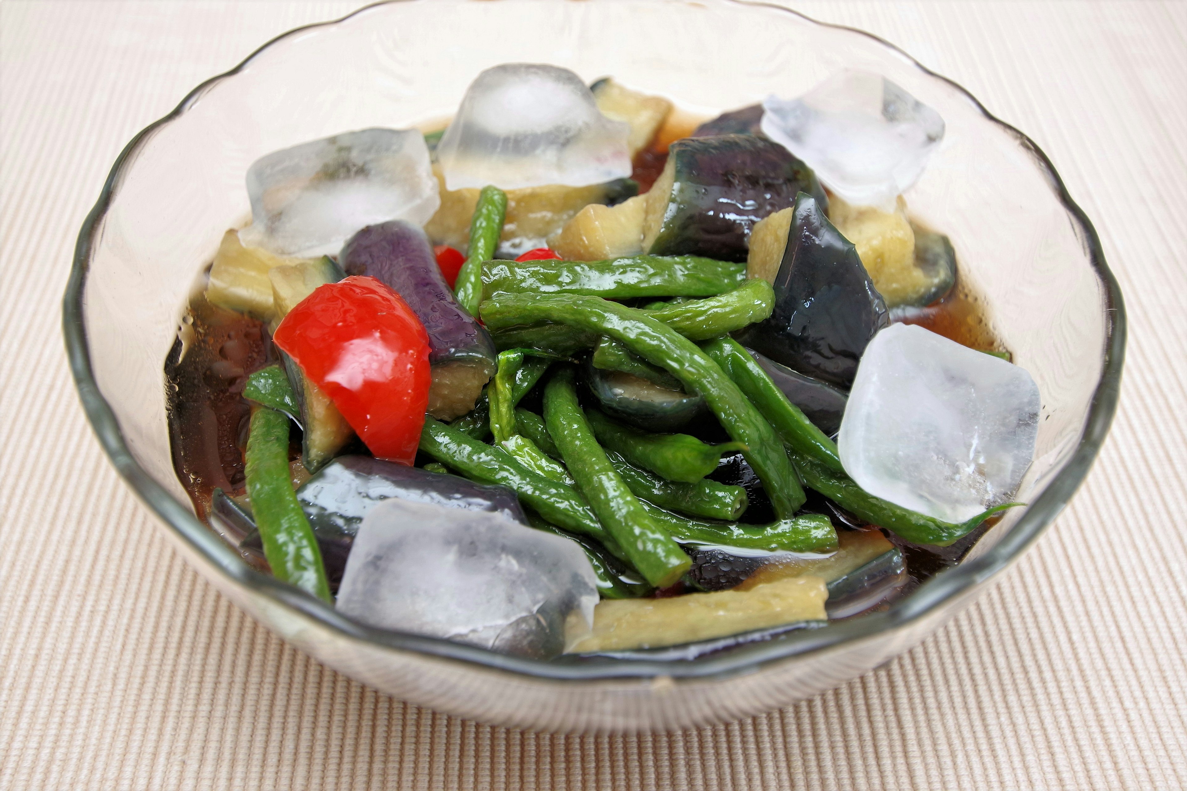 Gekühlter Gemüsesalat in einer Glasschüssel mit Eis und rotem Paprika