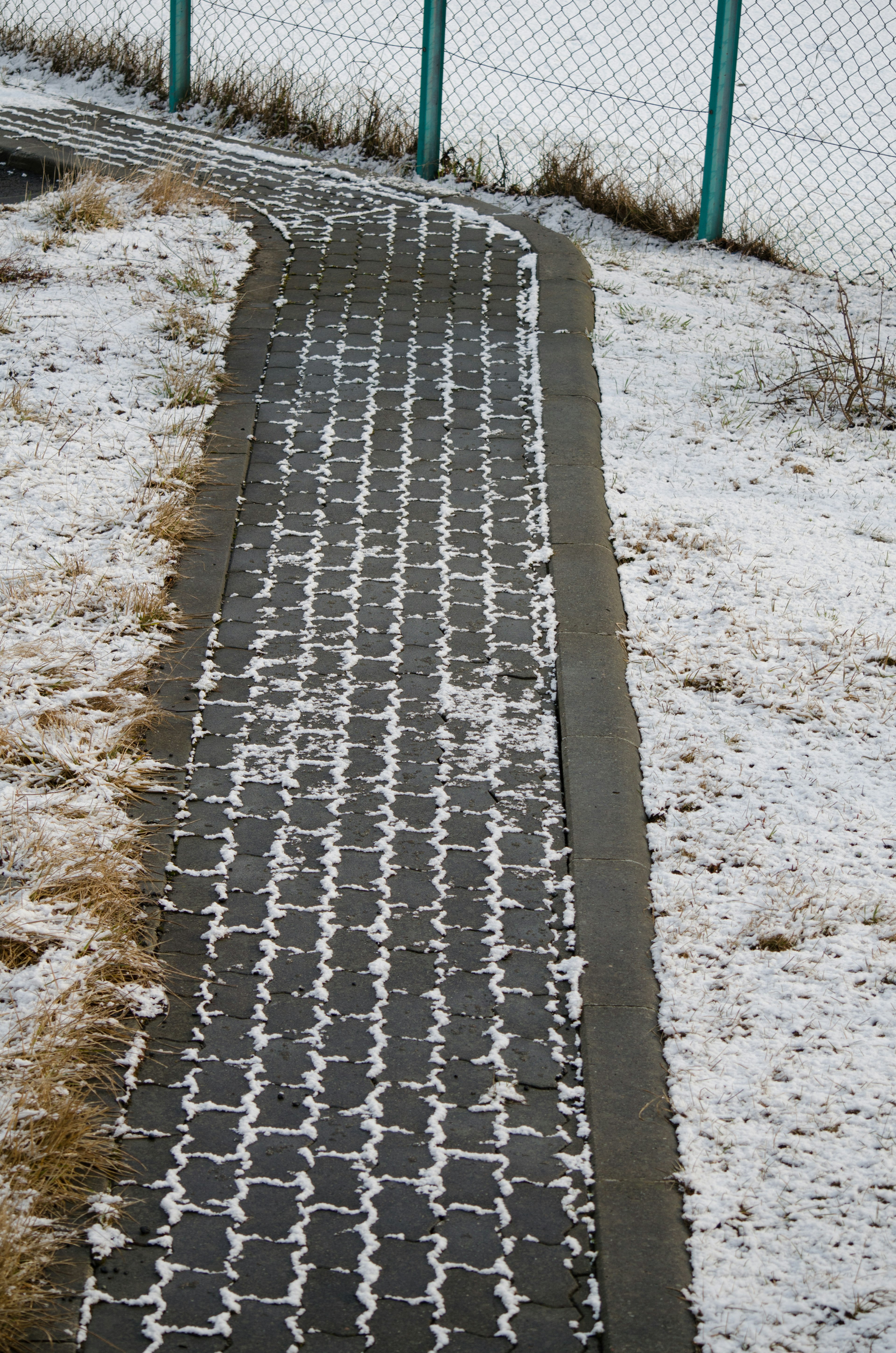 弯曲的铺砌人行道被雪覆盖