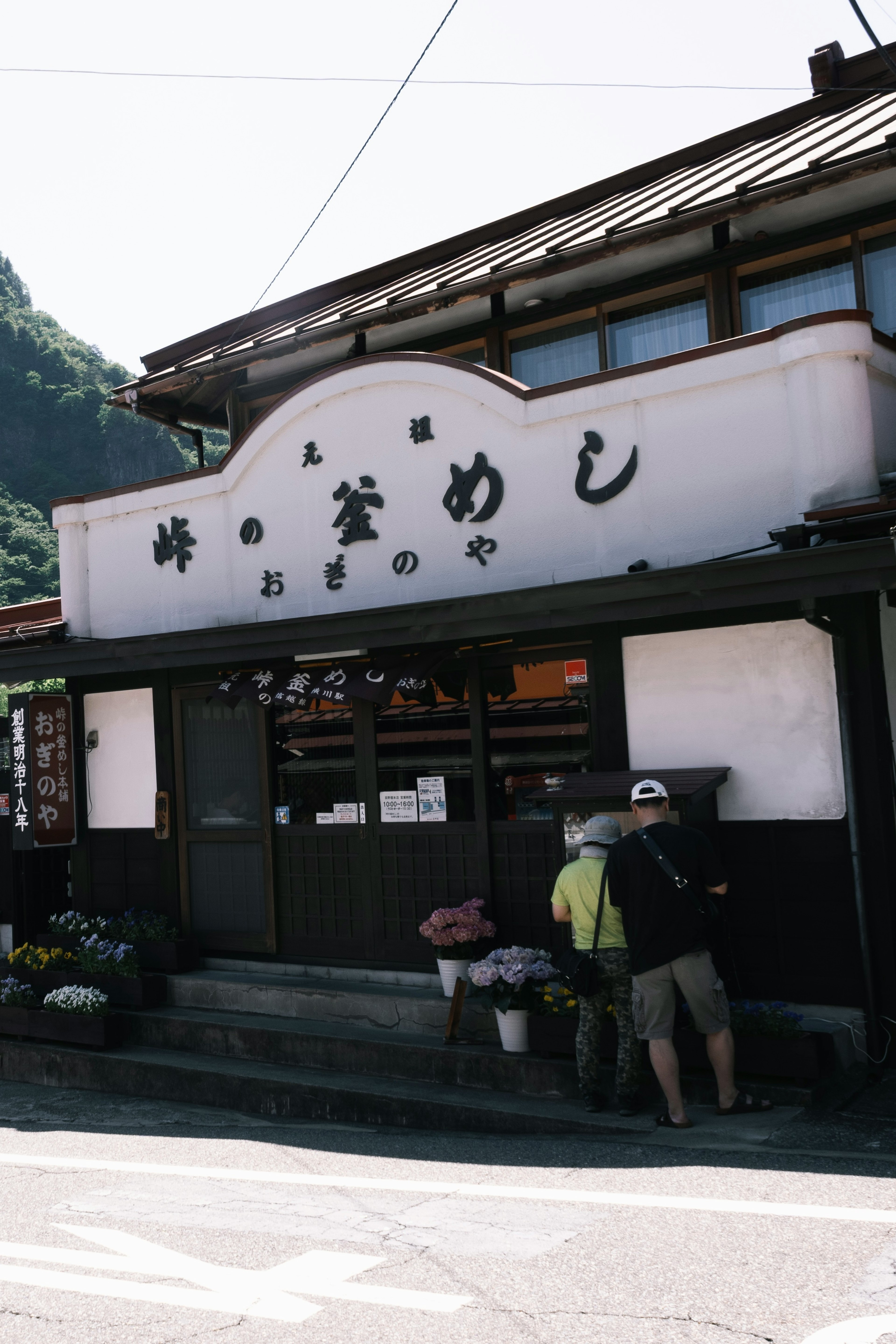 Eksterior rumah makan tradisional Jepang yang terletak di pegunungan dengan papan nama bertuliskan 'Restoran'