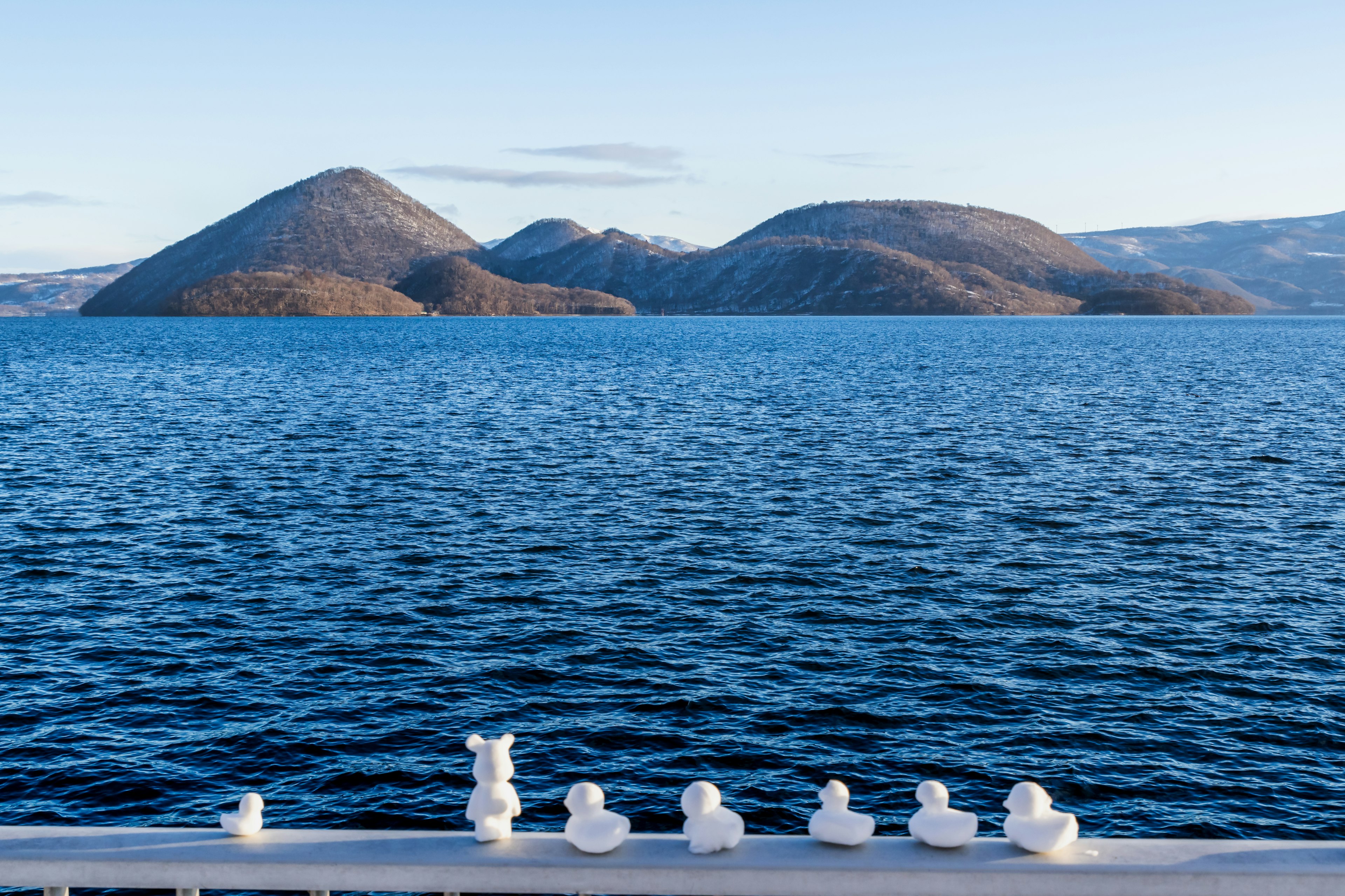 Objetos blancos alineados en la orilla de un lago con montañas al fondo