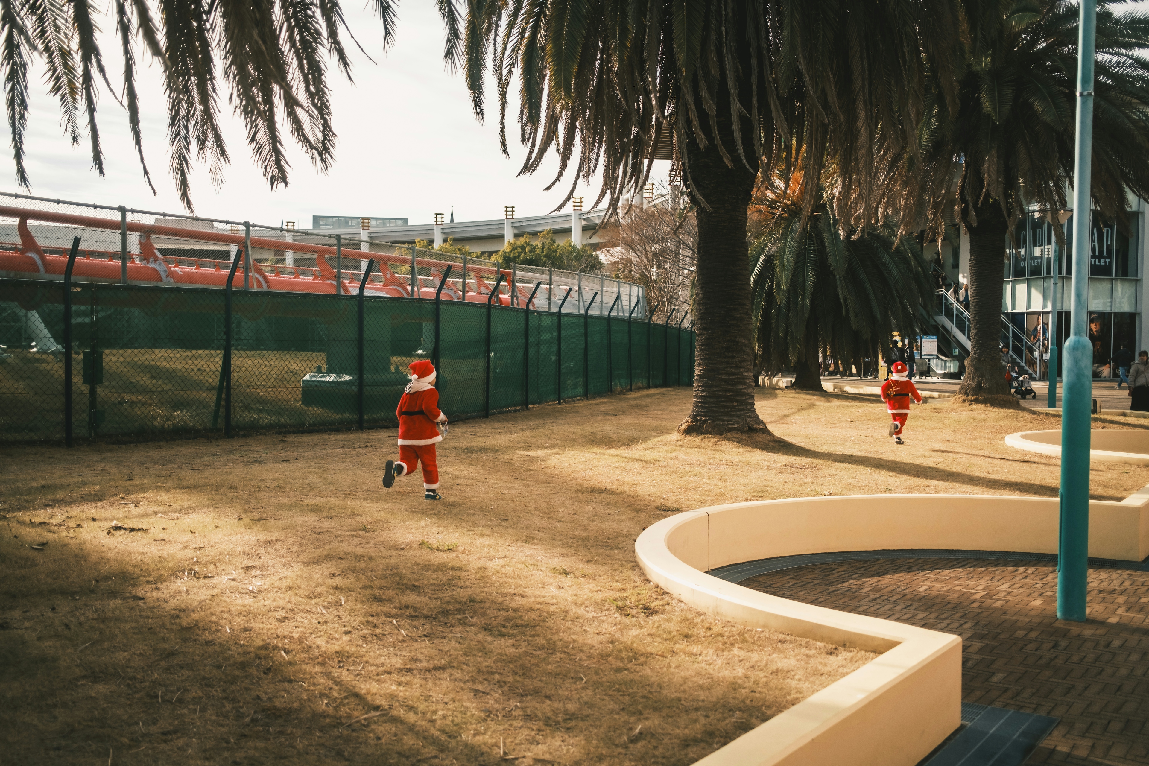 公園でサンタの衣装を着た二人の子供が走っている風景