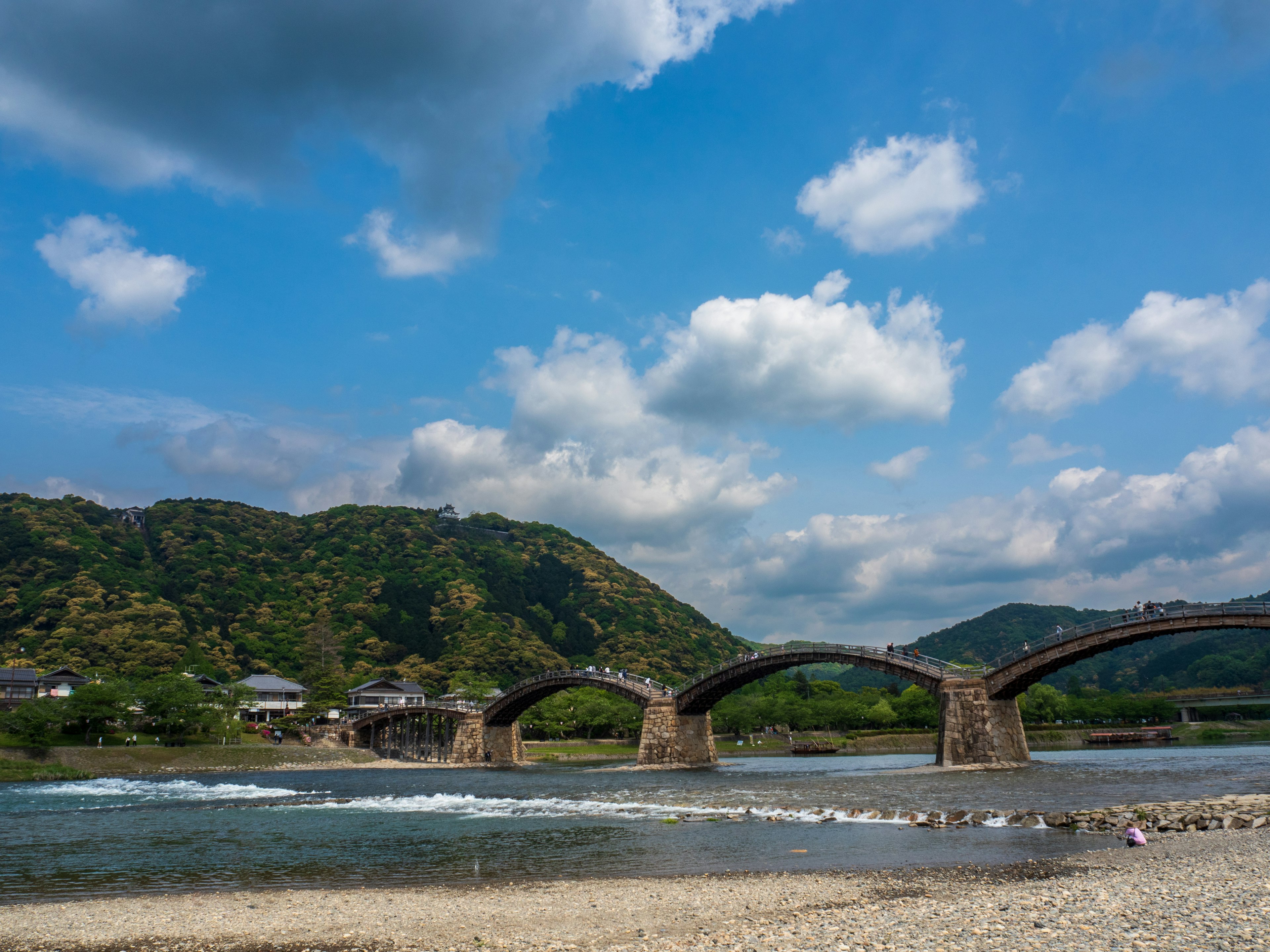 Scenic view of an arched bridge over a river with mountains in the background