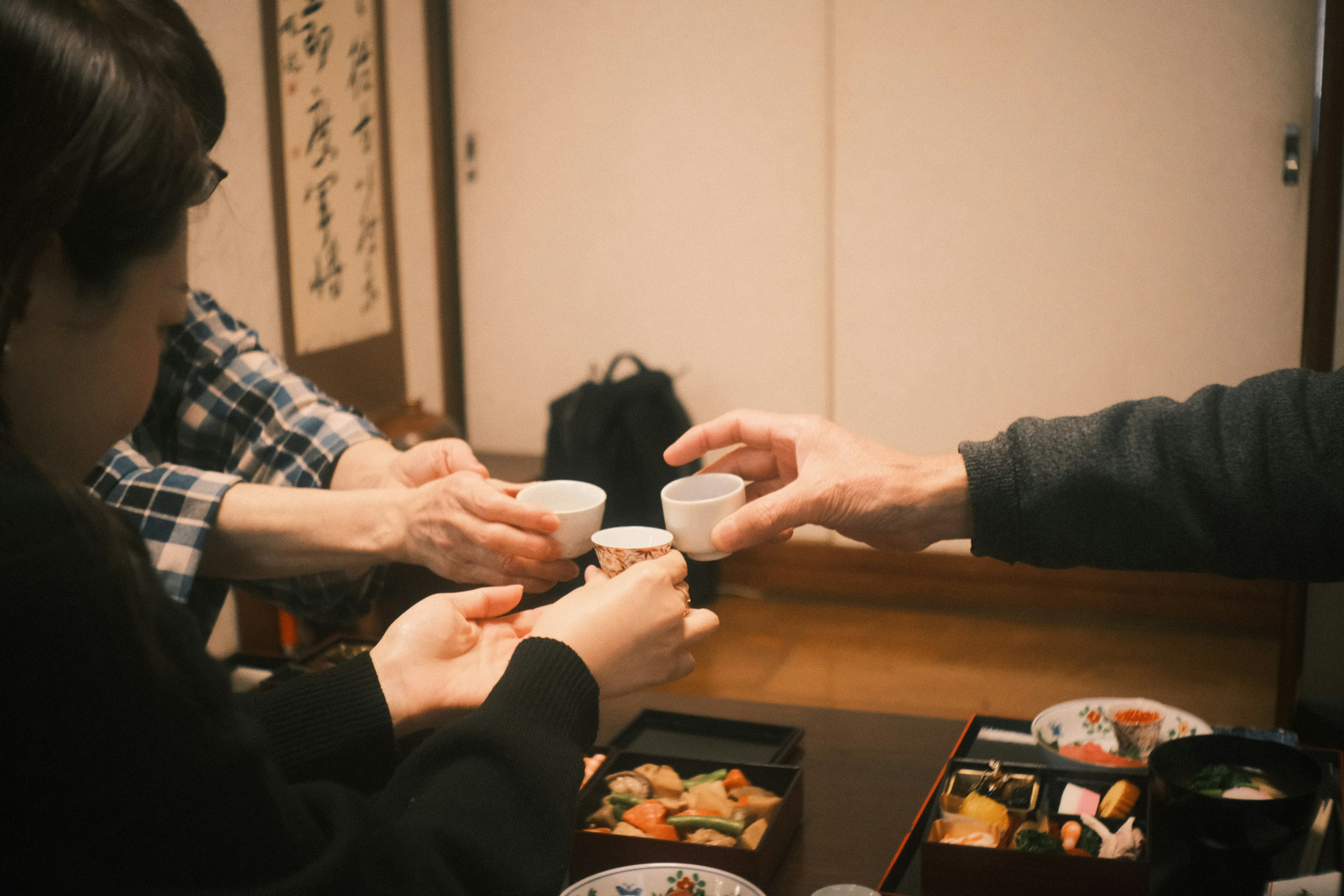 Freunde stoßen mit Bechern an traditionelle japanische Küche auf dem Tisch