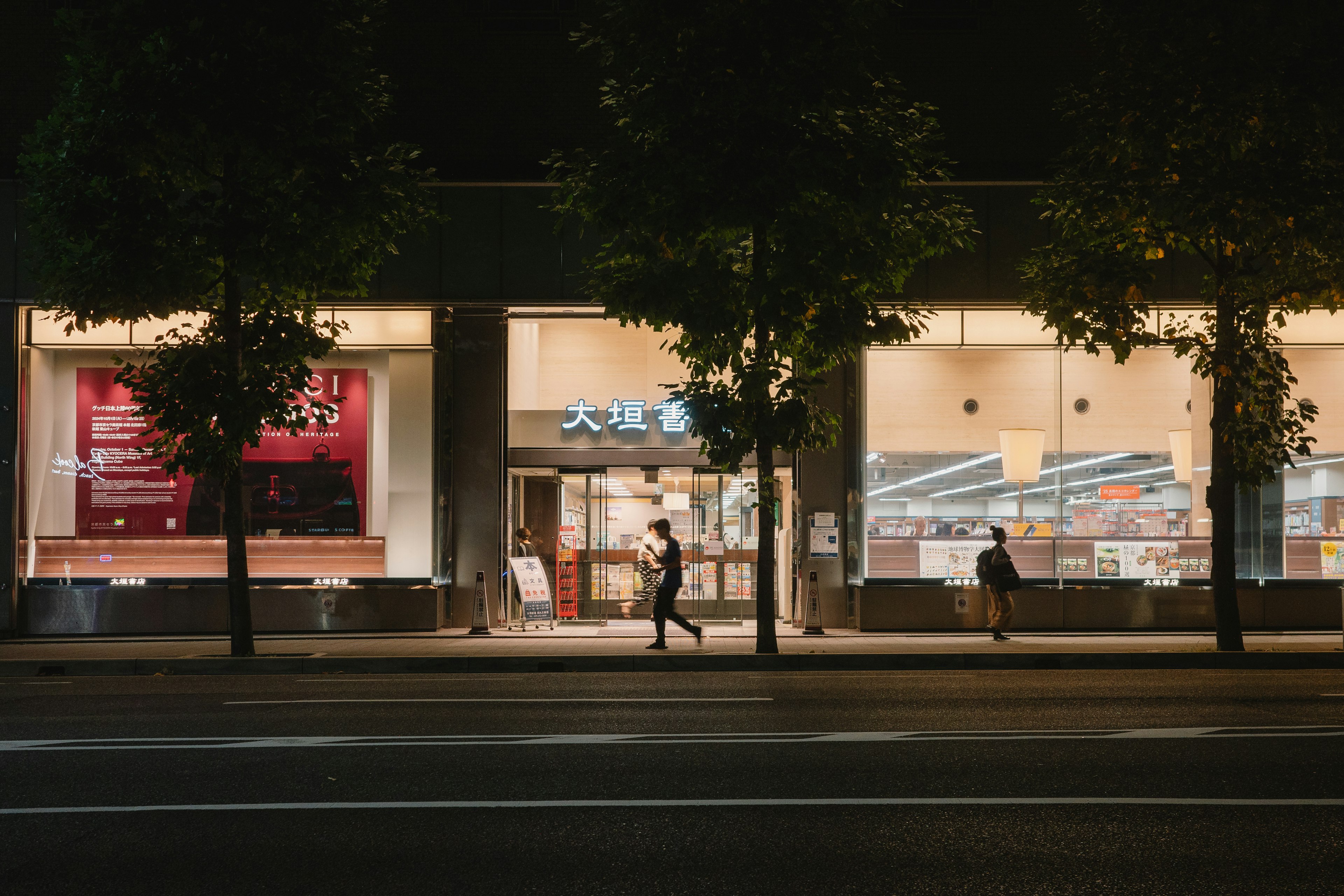 Bright storefront at night with pedestrians