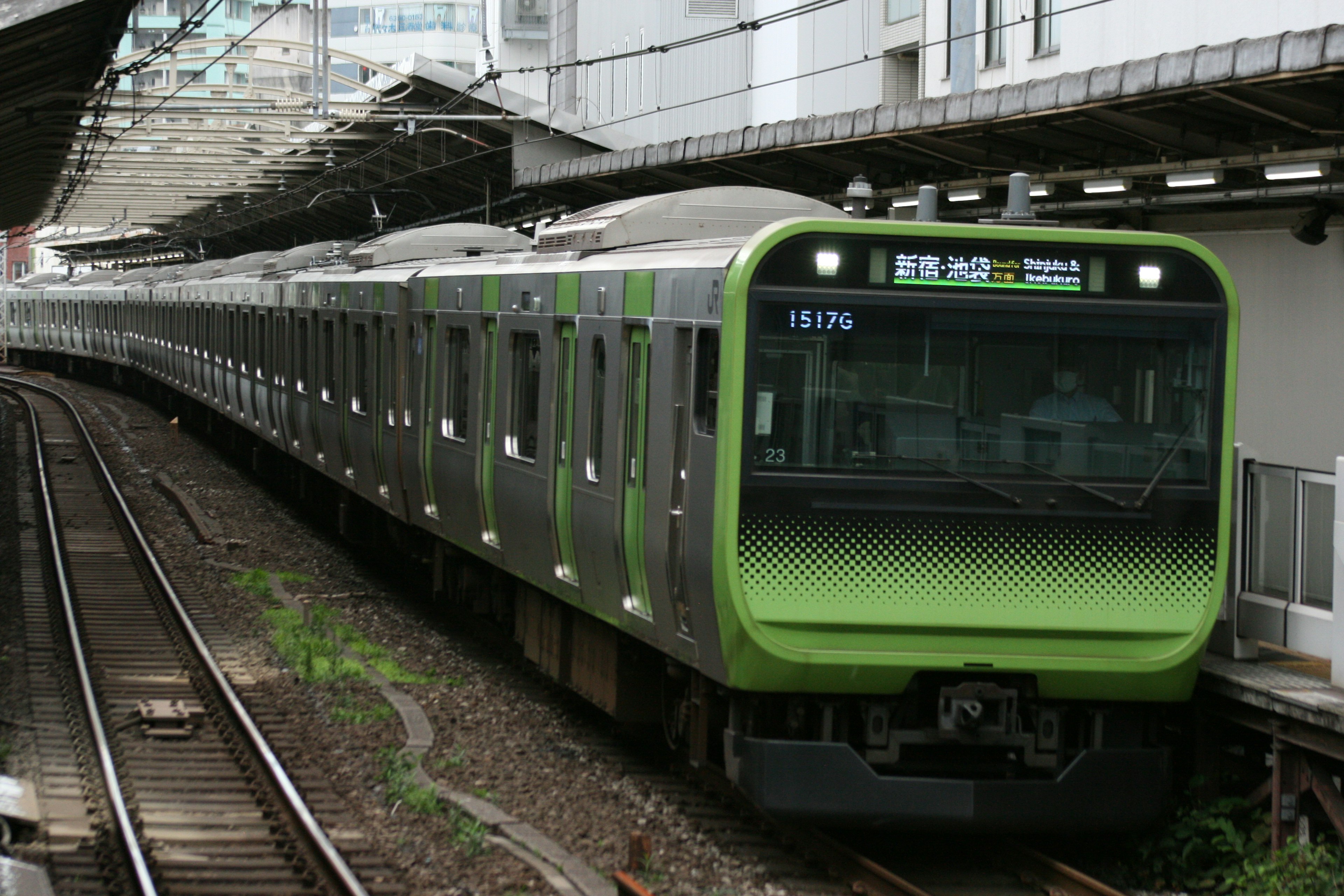 城市背景中的綠色火車在軌道上行駛