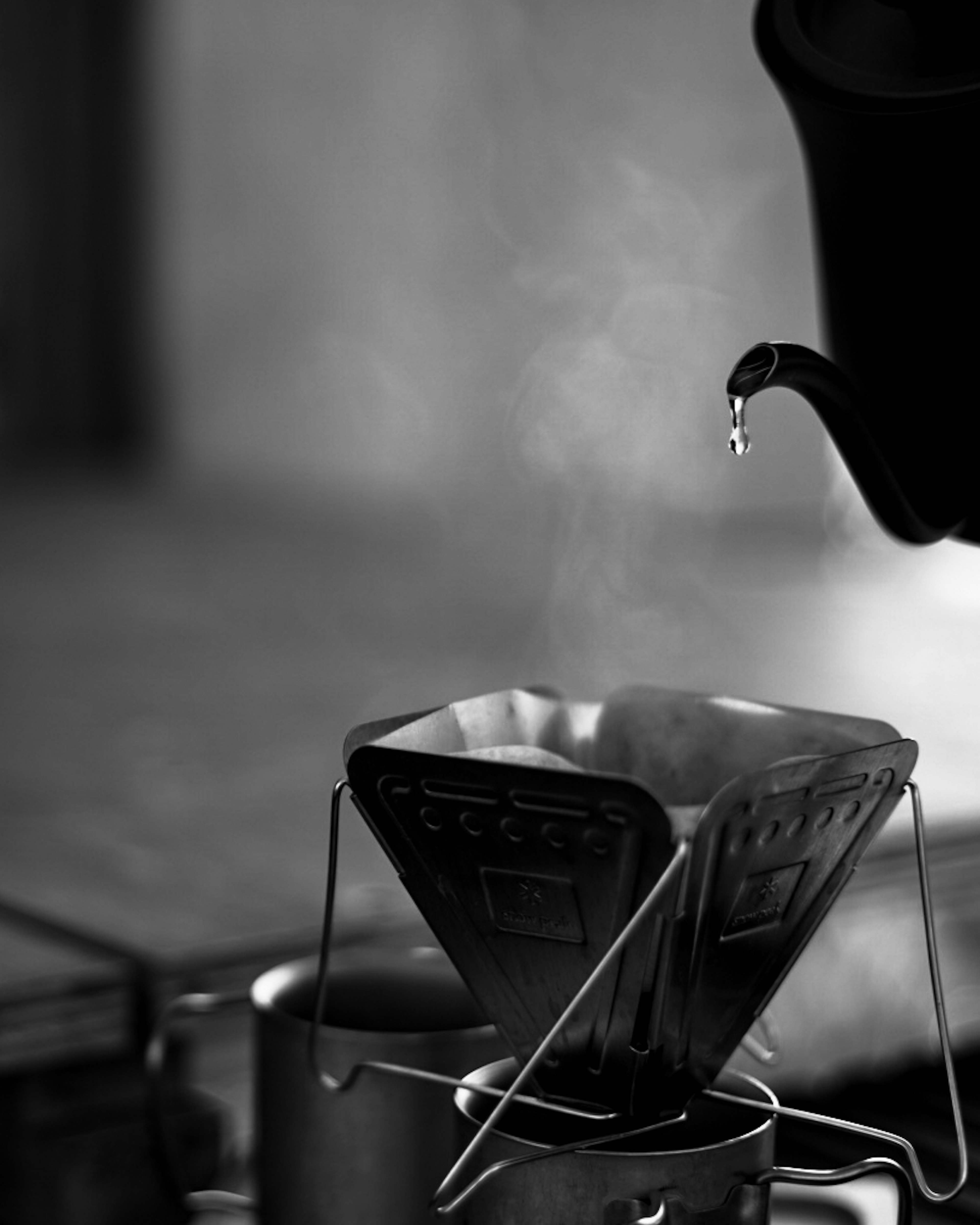 Black and white image of a coffee dripper with steam rising