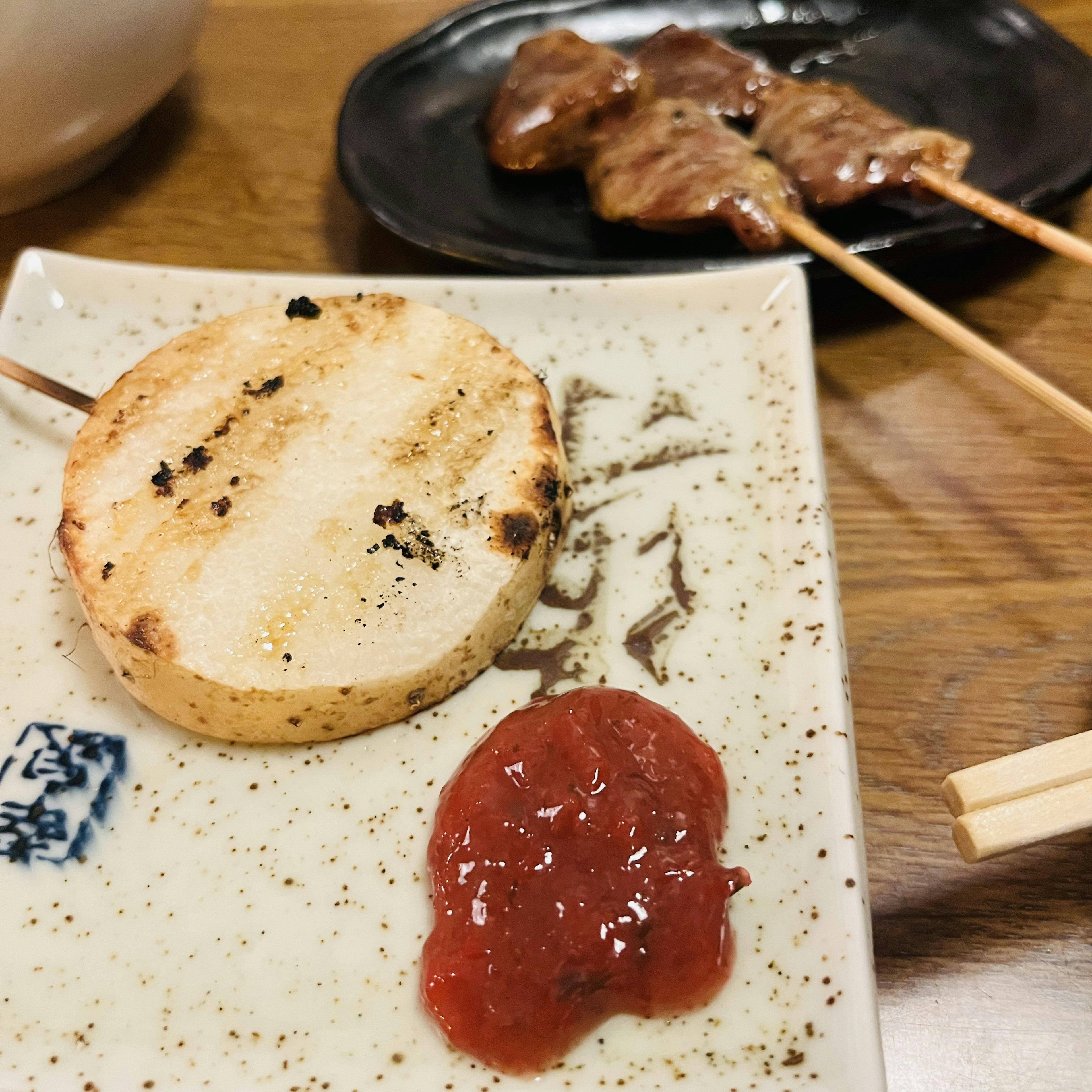 焼き餅と肉の串焼きが並ぶ皿の上にある