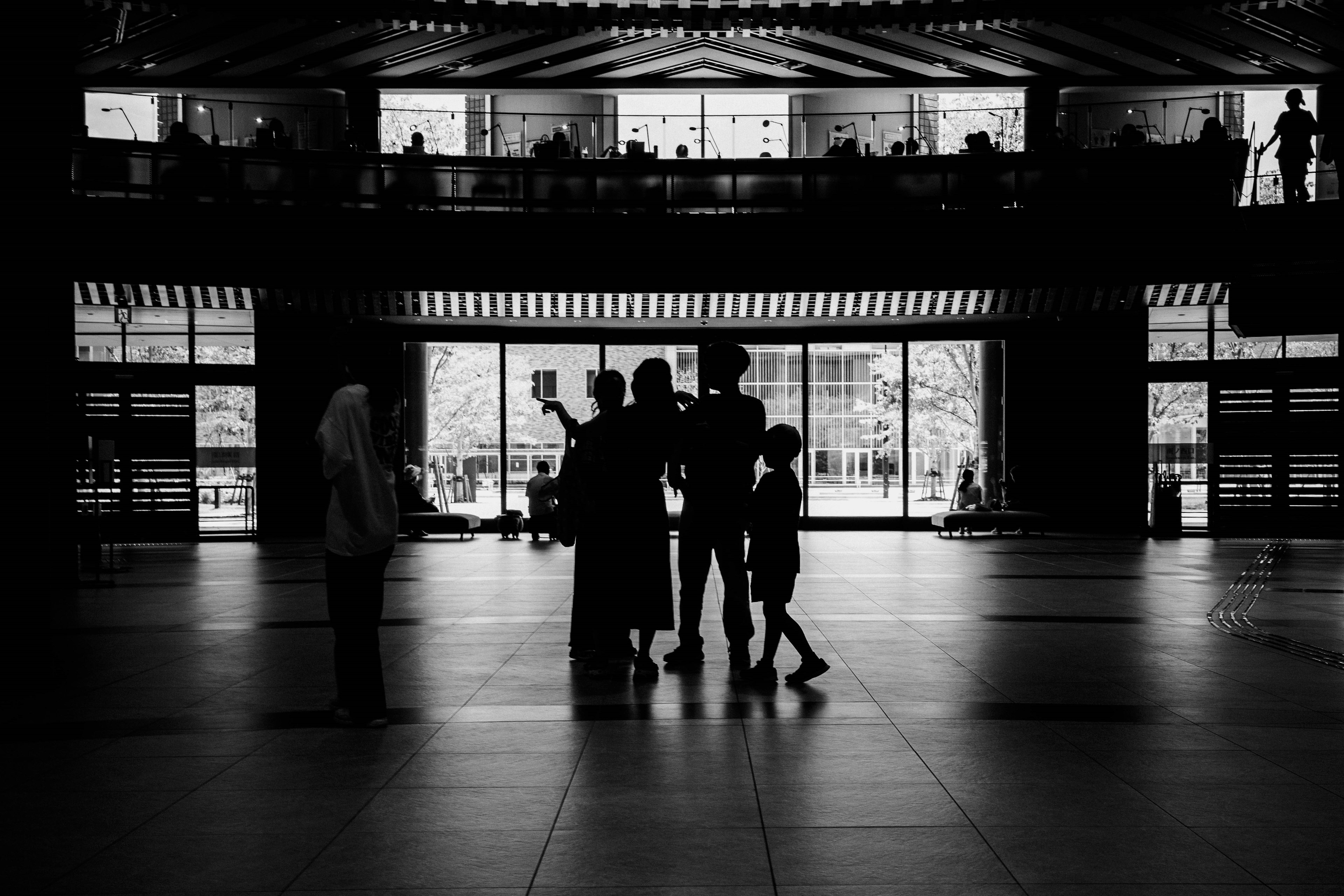 Silhouetted people inside a building with natural light streaming through windows and stairs