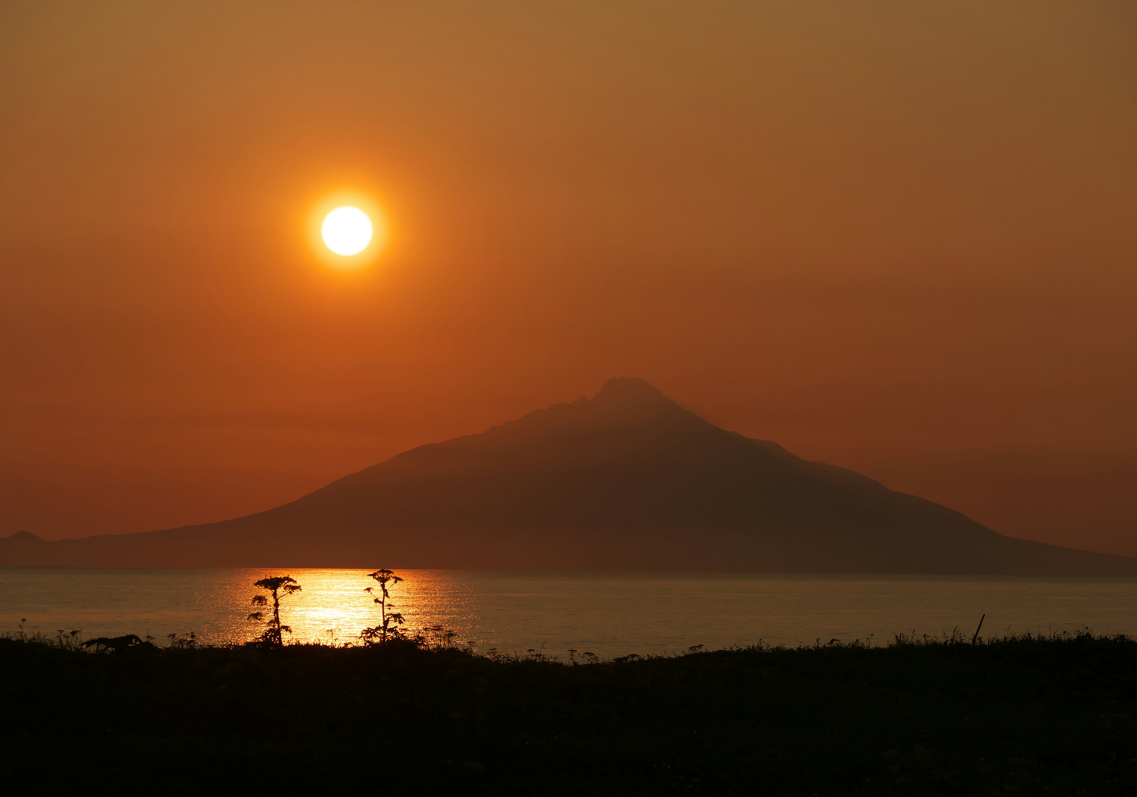 Scenic view of a sunset over a mountain reflecting on calm water