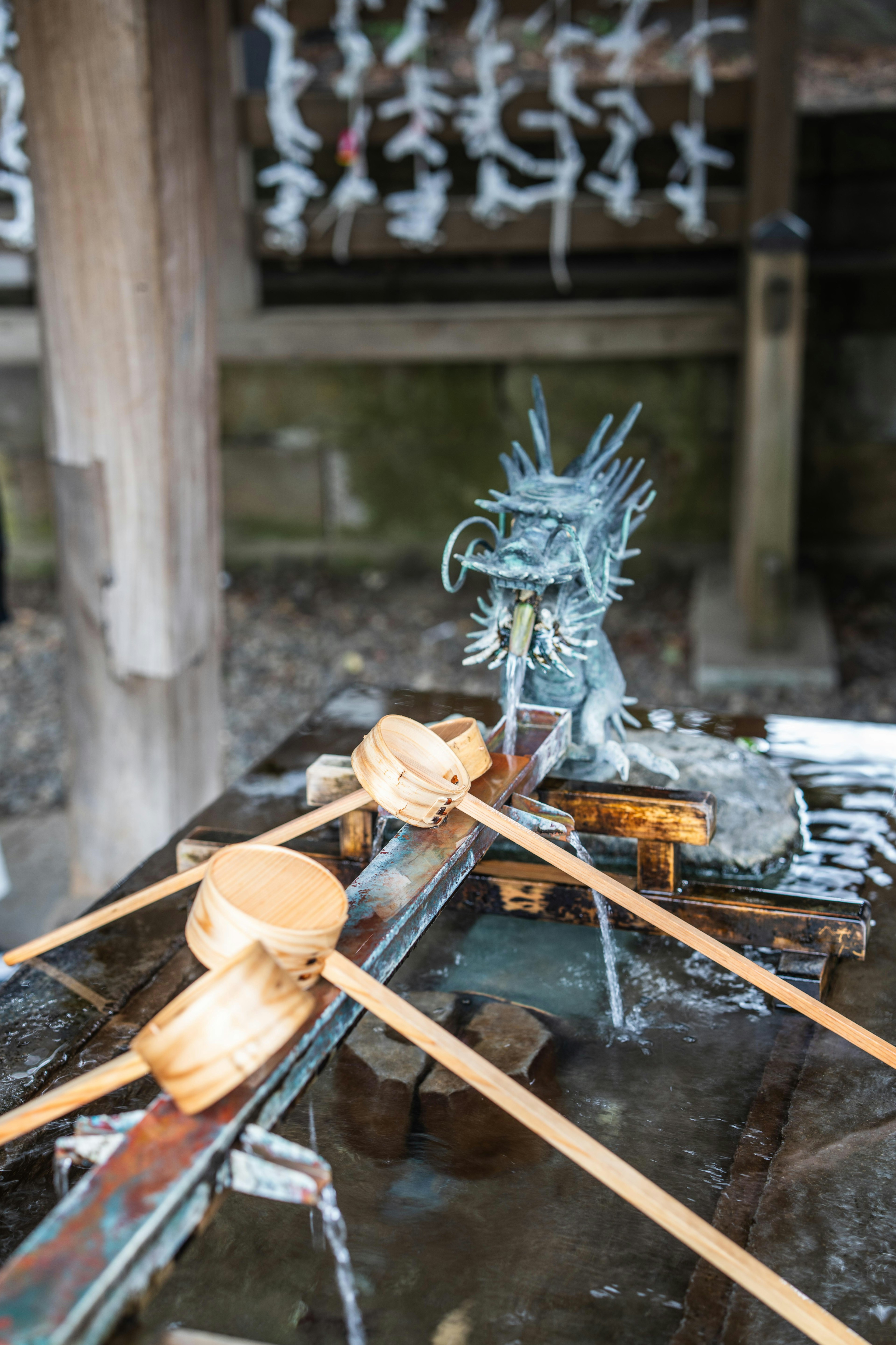 Temizuya mit Holzlöffeln und einer blauen Drachenskulptur in einem Schrein