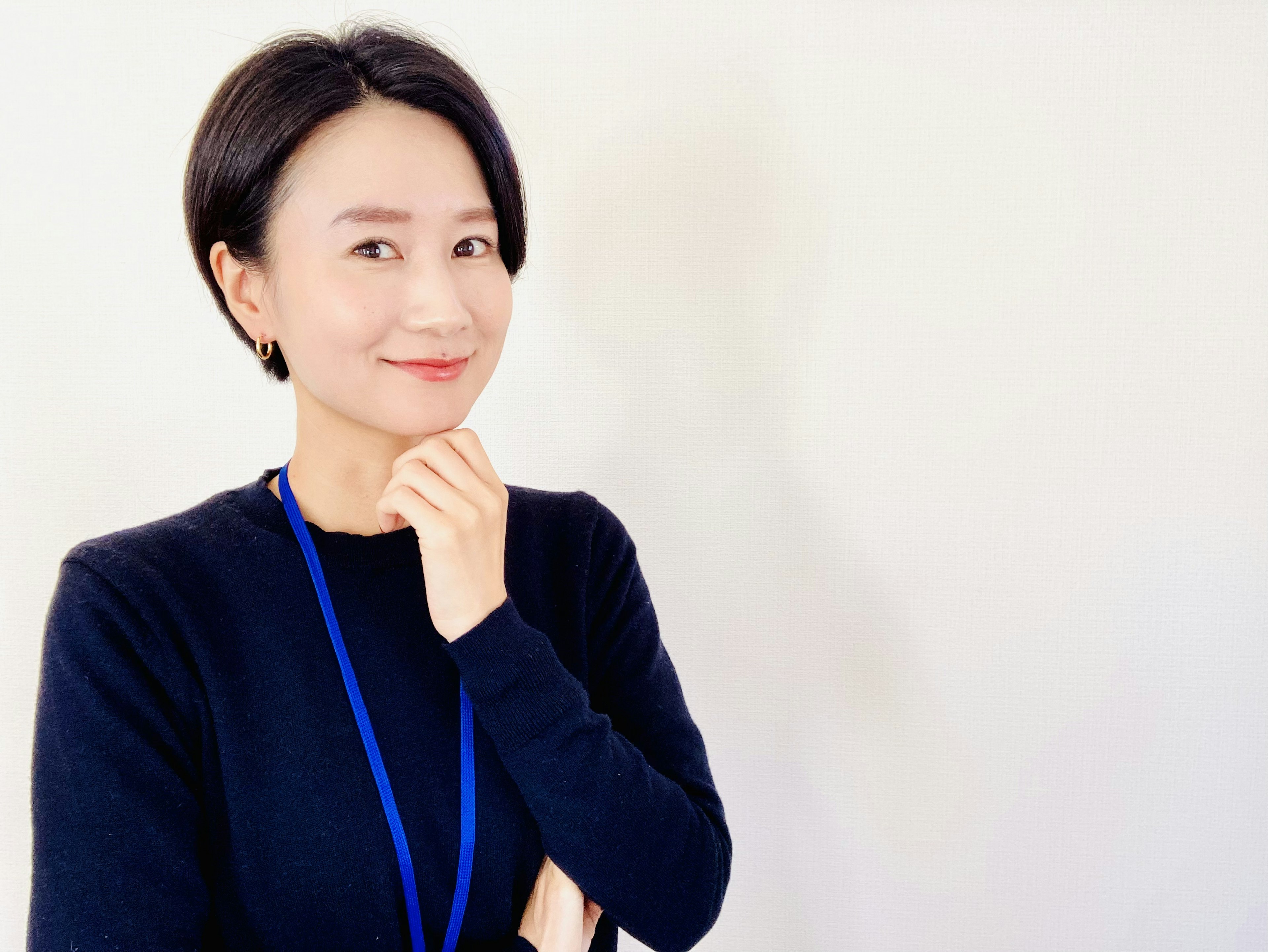 A woman smiling with her hand on her chin against a white background