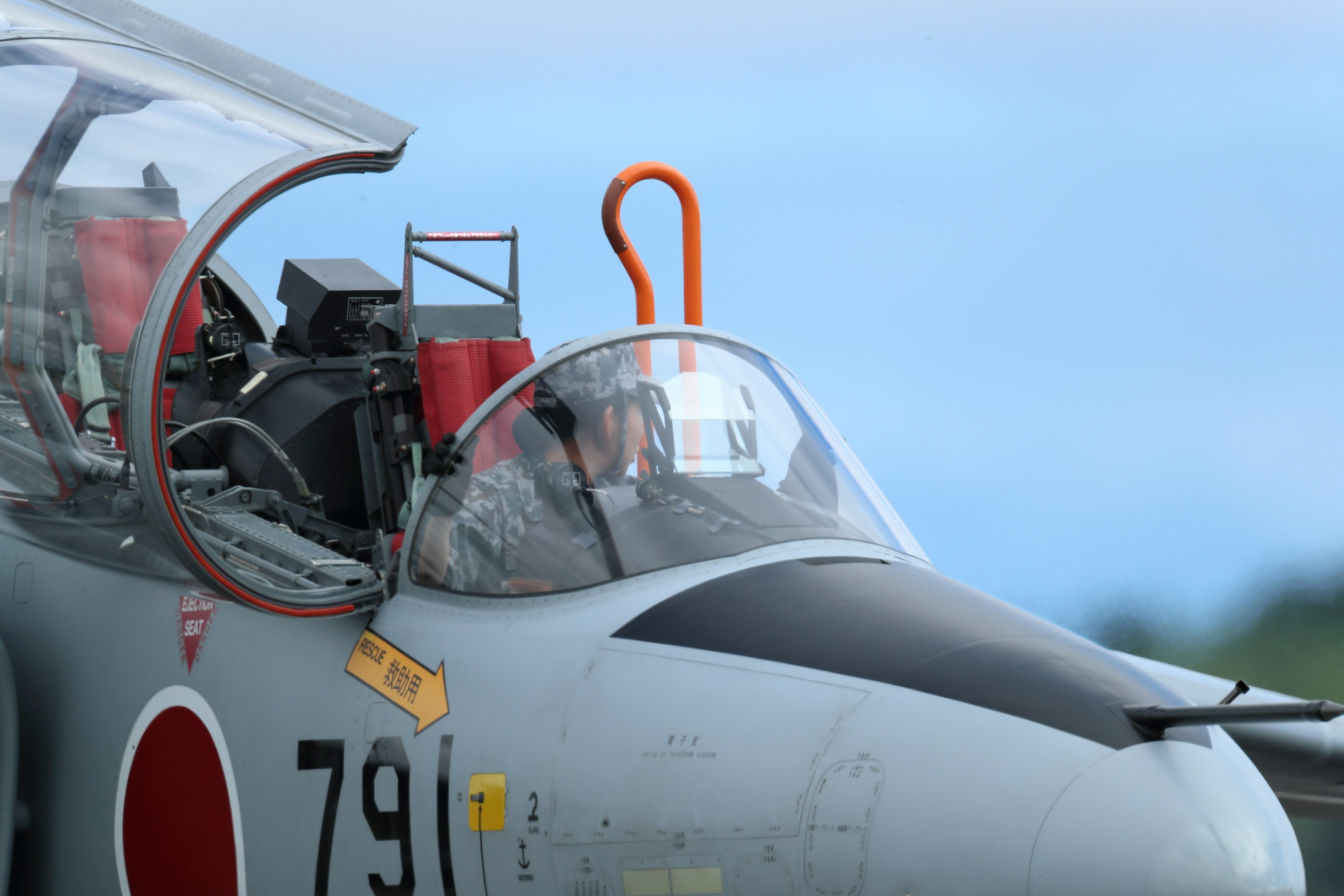 Acercamiento al cockpit de un caza con un asa roja prominente