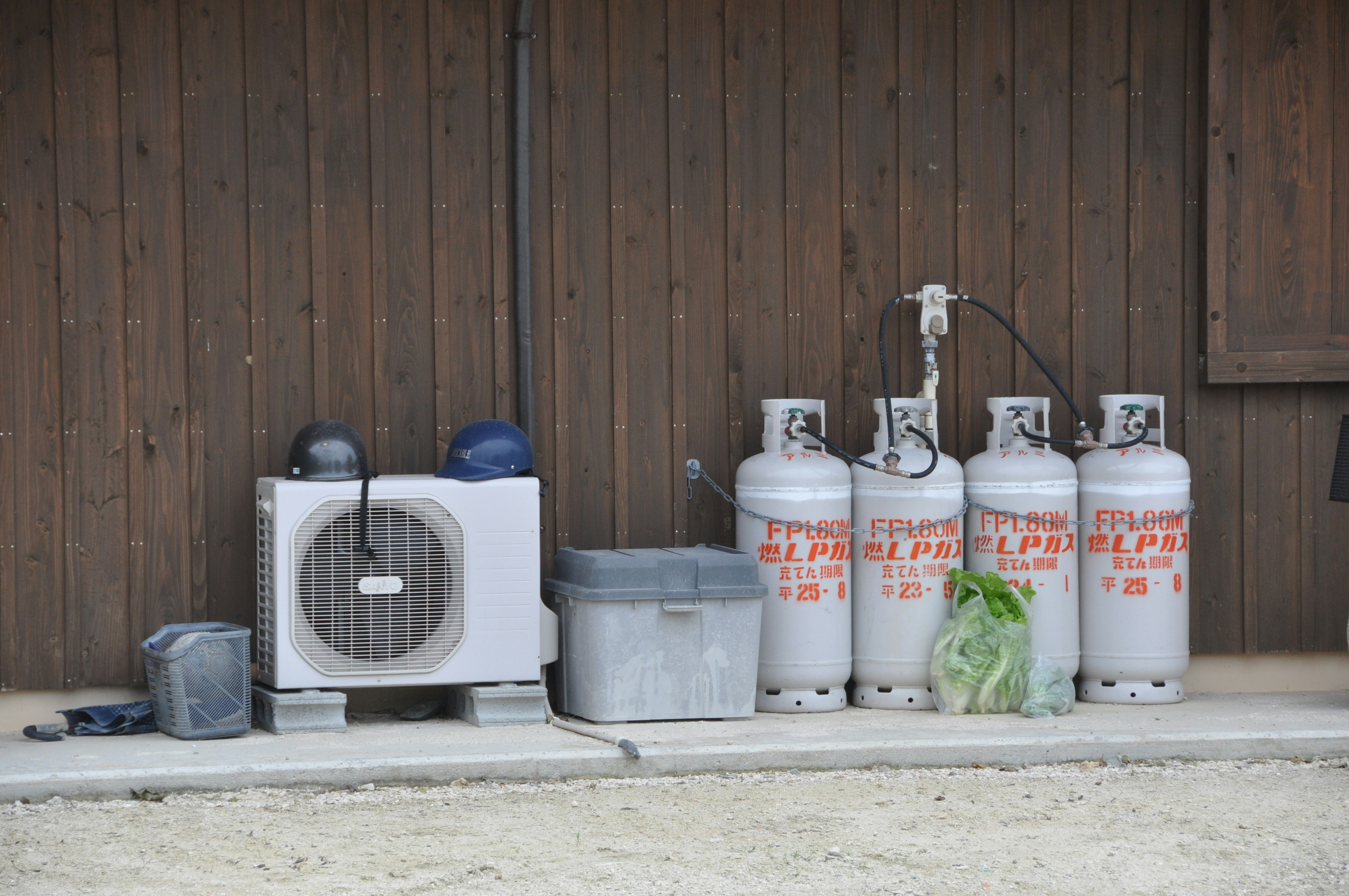 Air conditioning unit and propane gas cylinders against a wooden wall