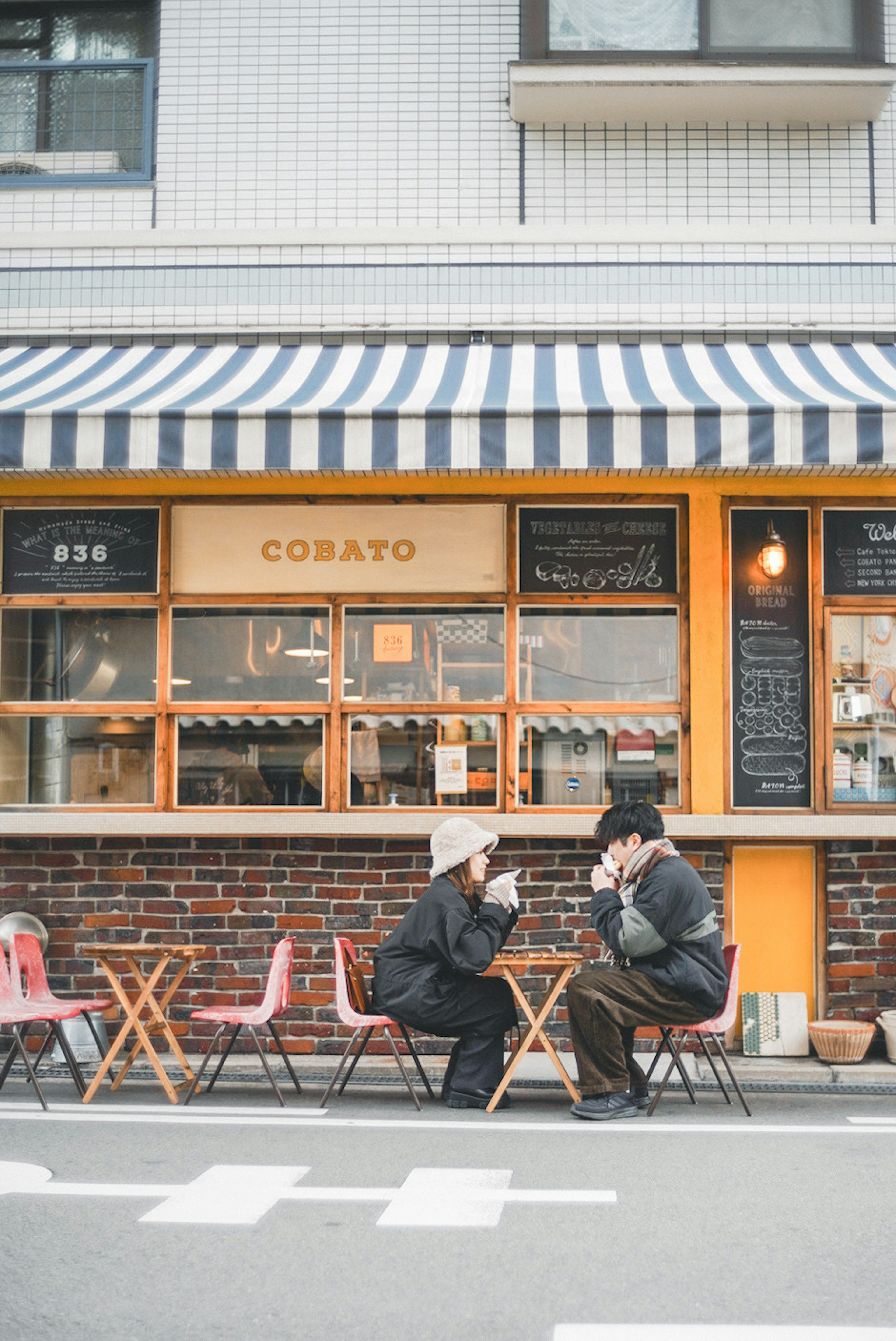 Two people enjoying conversation outside a café with striped awning