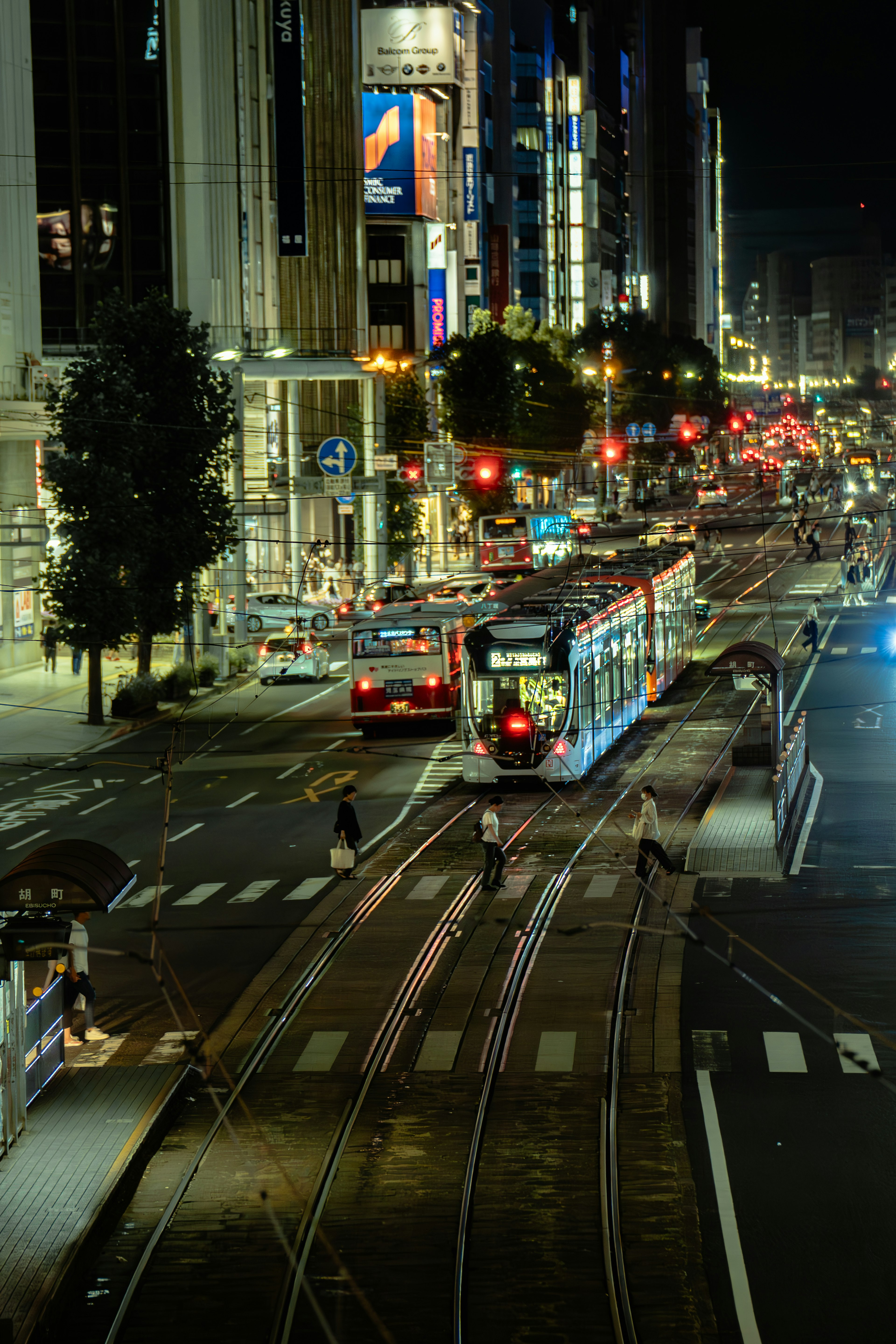 Paesaggio urbano notturno con tram e veicoli a un incrocio