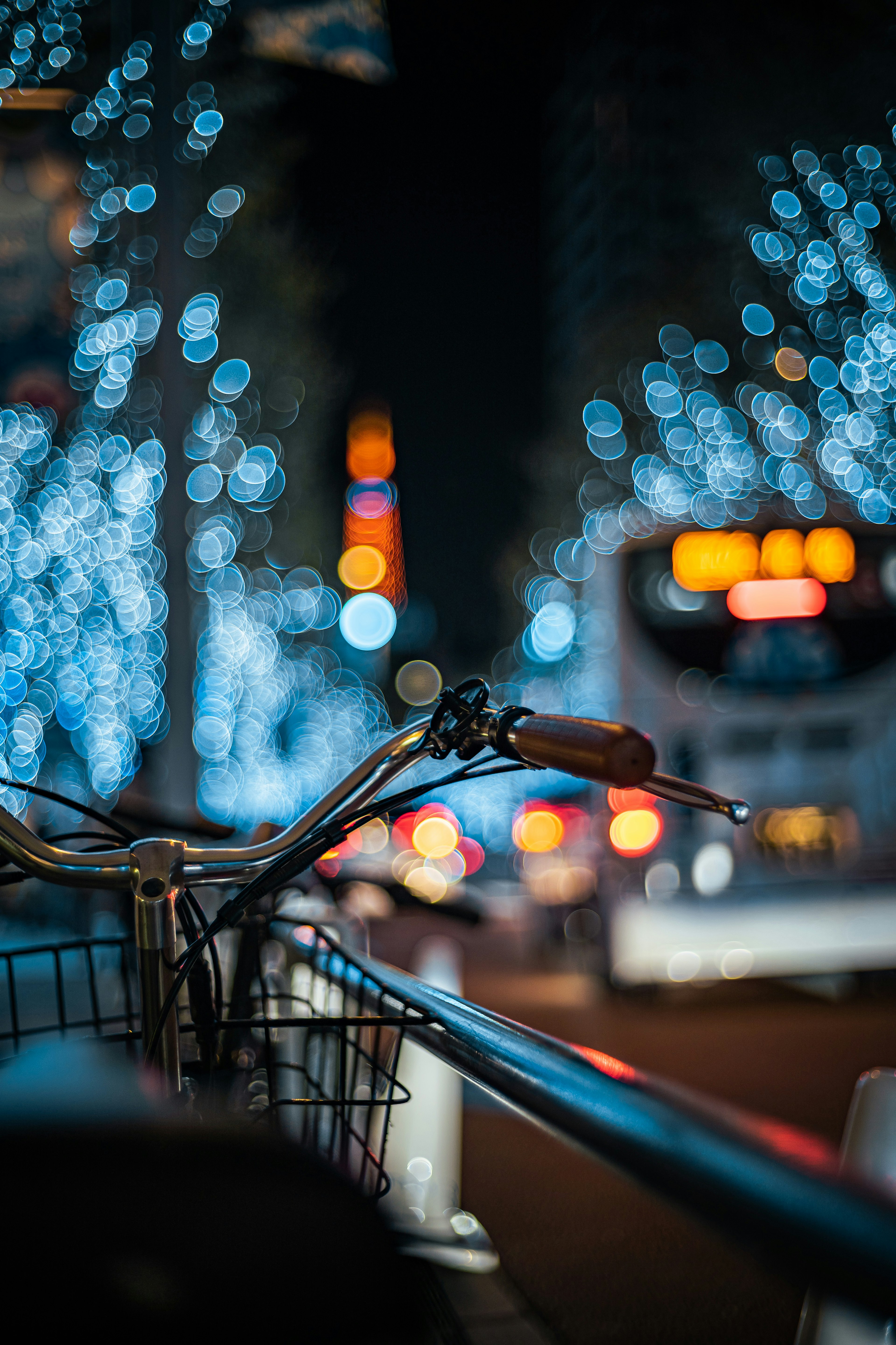 Poignée de vélo au premier plan avec des lumières bleues en arrière-plan la nuit