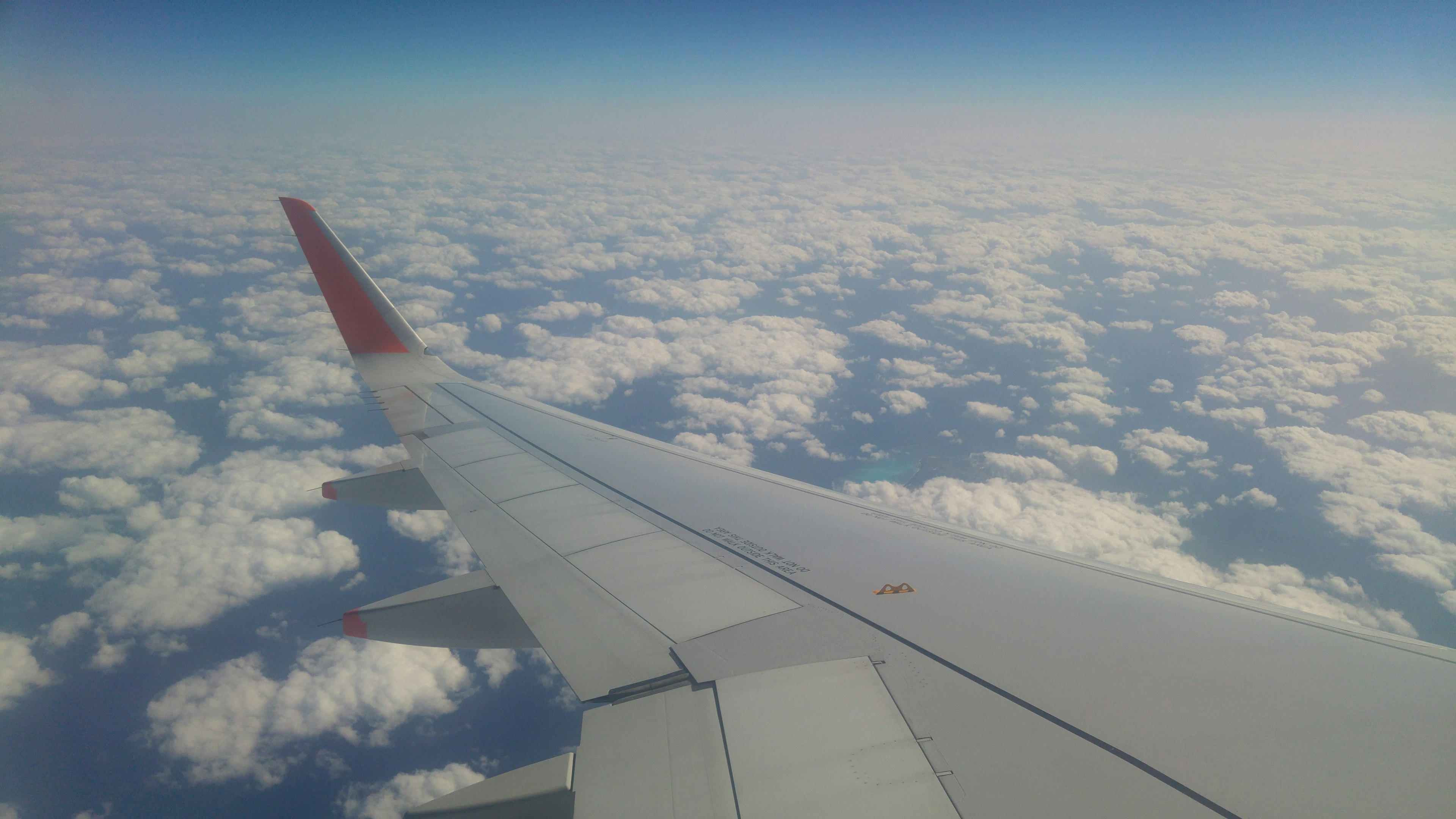 View of an airplane wing above a sea of clouds under a blue sky