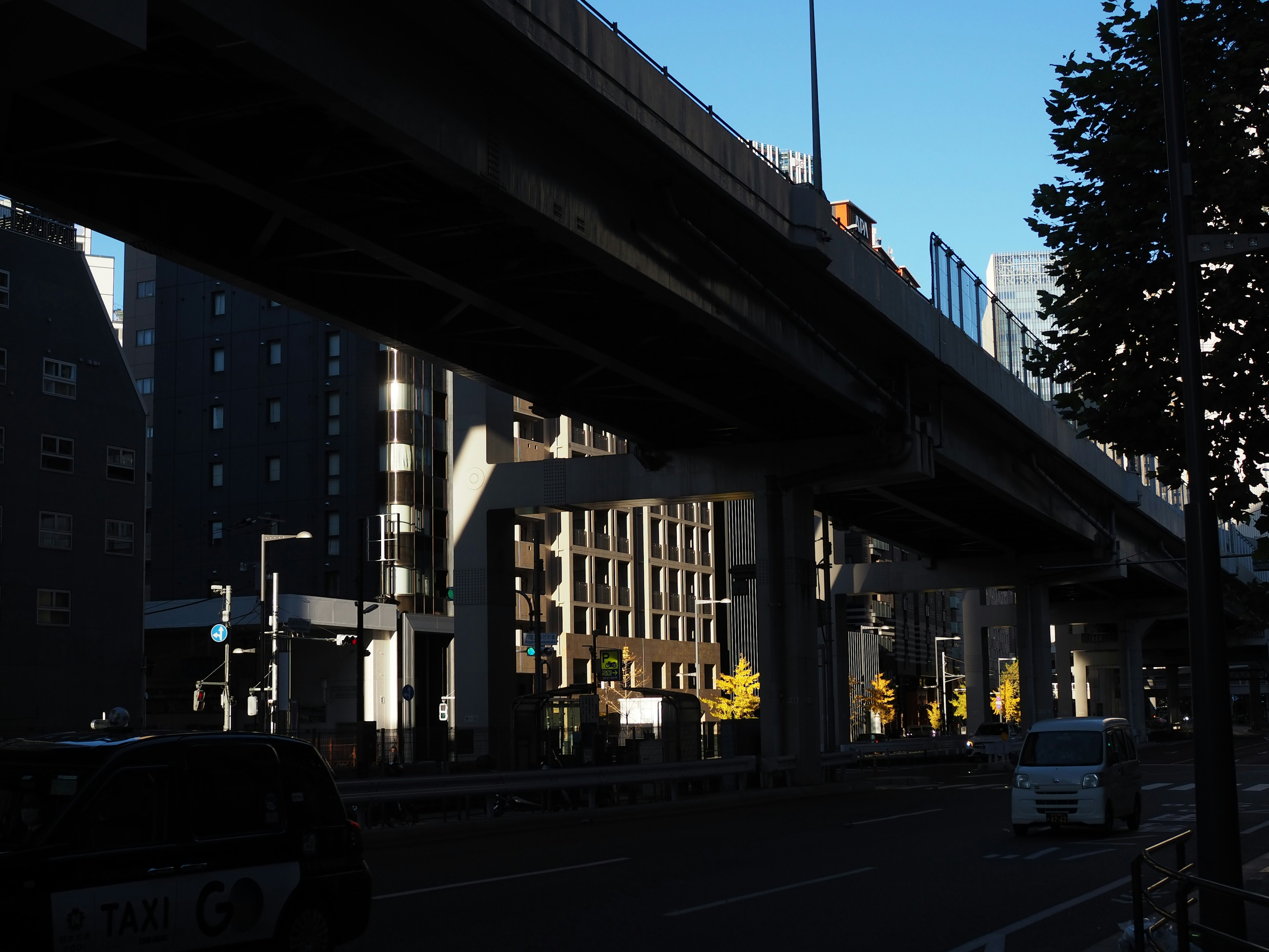 Paysage urbain avec une autoroute surélevée projetant des ombres sur la rue