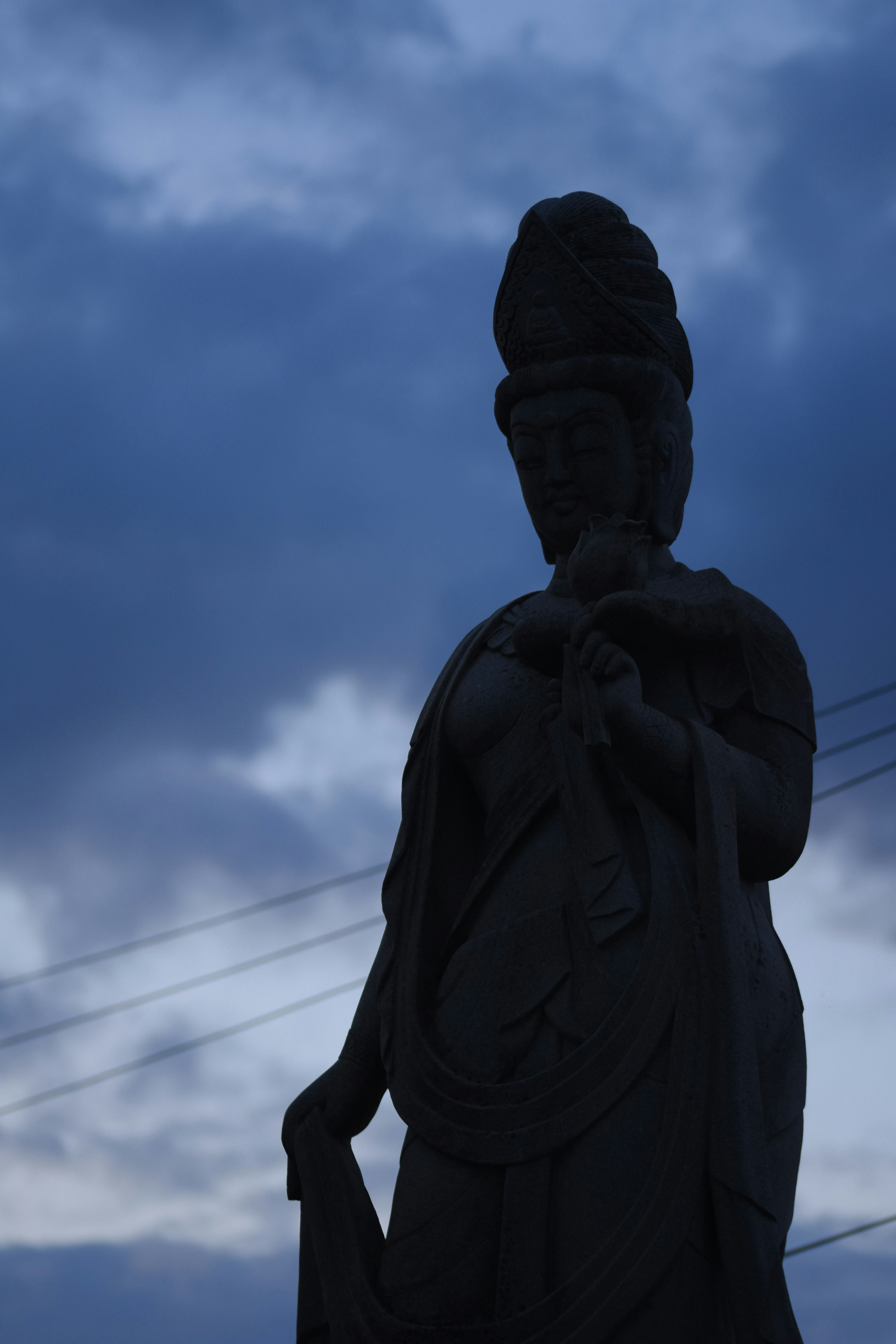 Silhouette einer dunklen Statue vor einem bewölkten Himmel