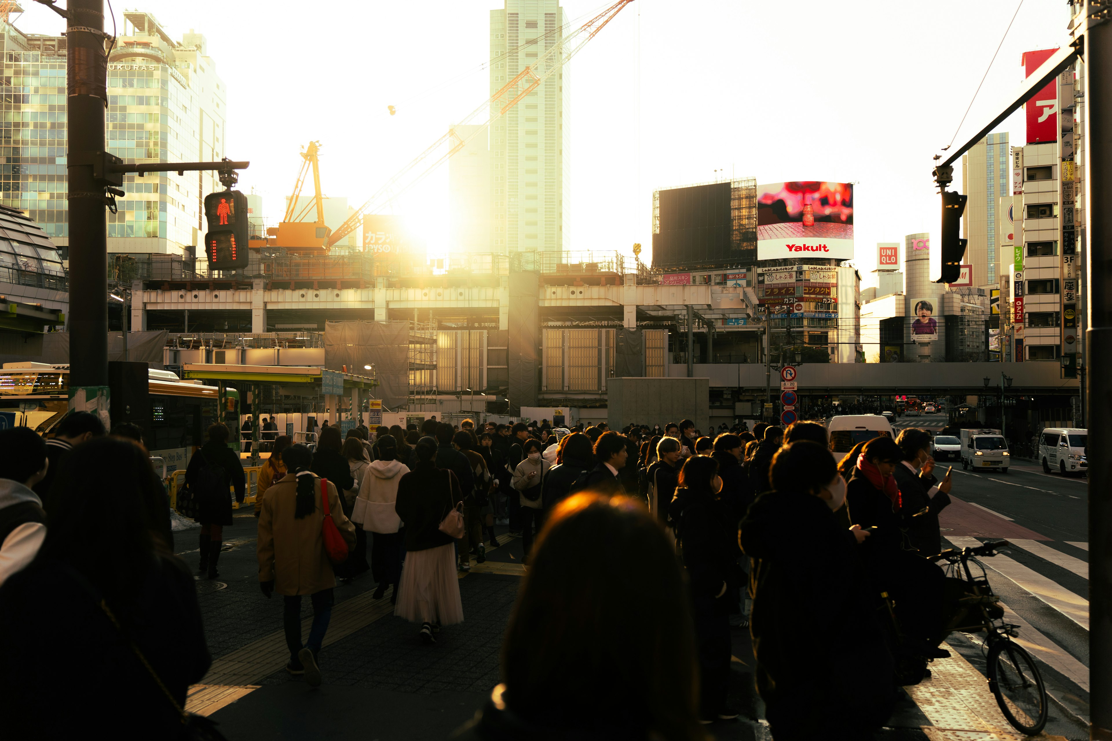 Foule de personnes à un carrefour animé avec le coucher de soleil en arrière-plan