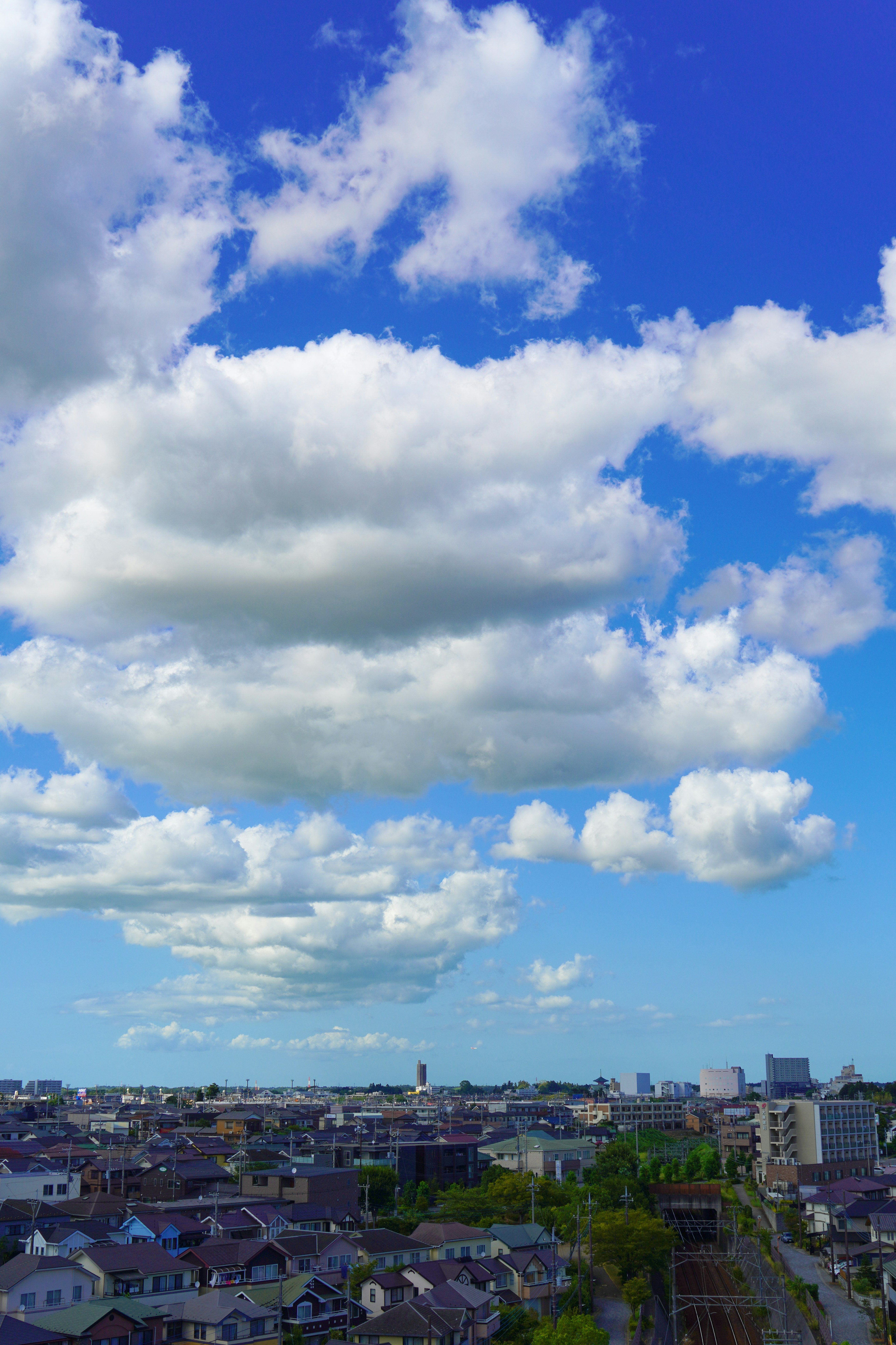 White clouds floating in a blue sky over a cityscape