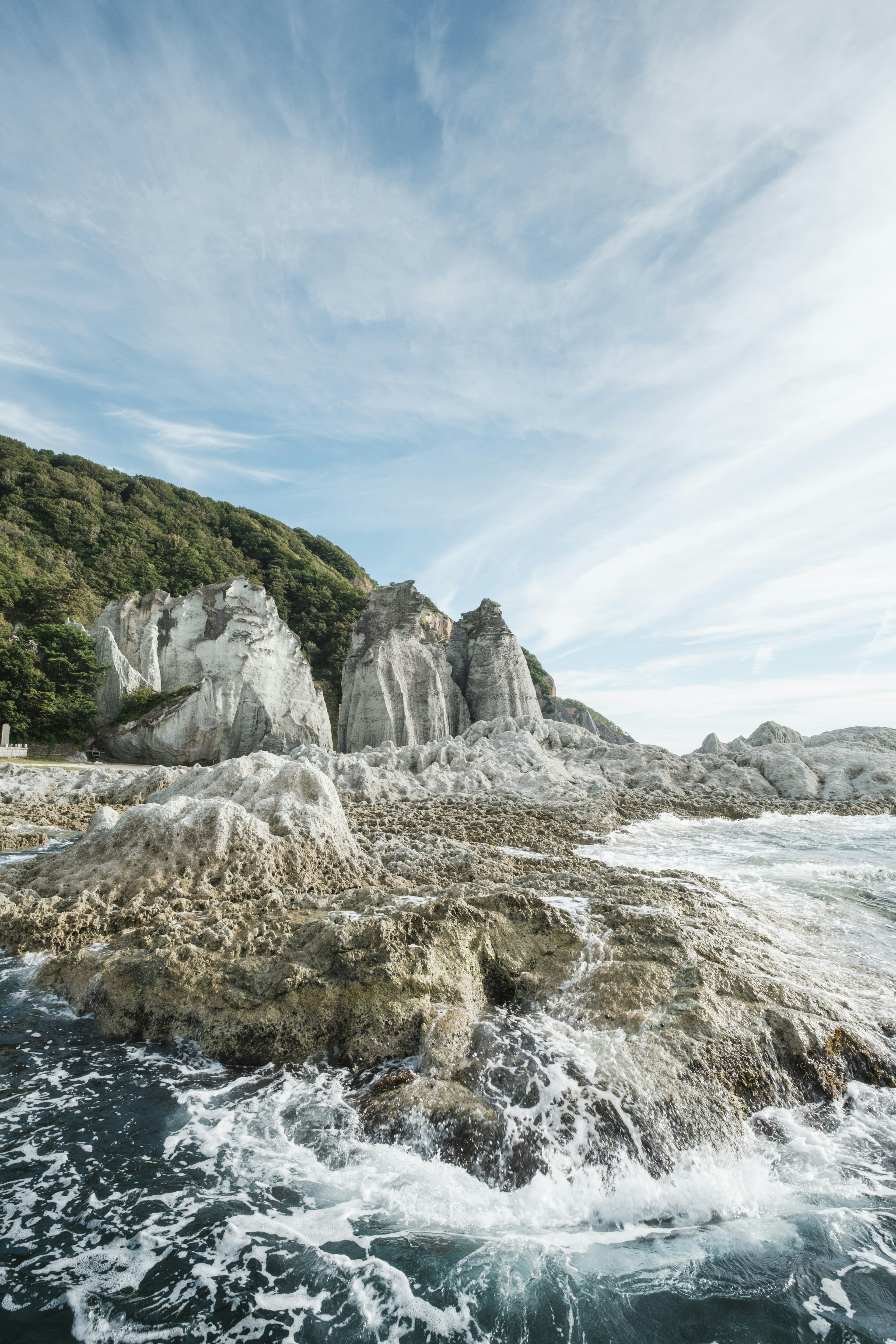 Paesaggio costiero con scogliere rocciose e onde sotto un cielo blu