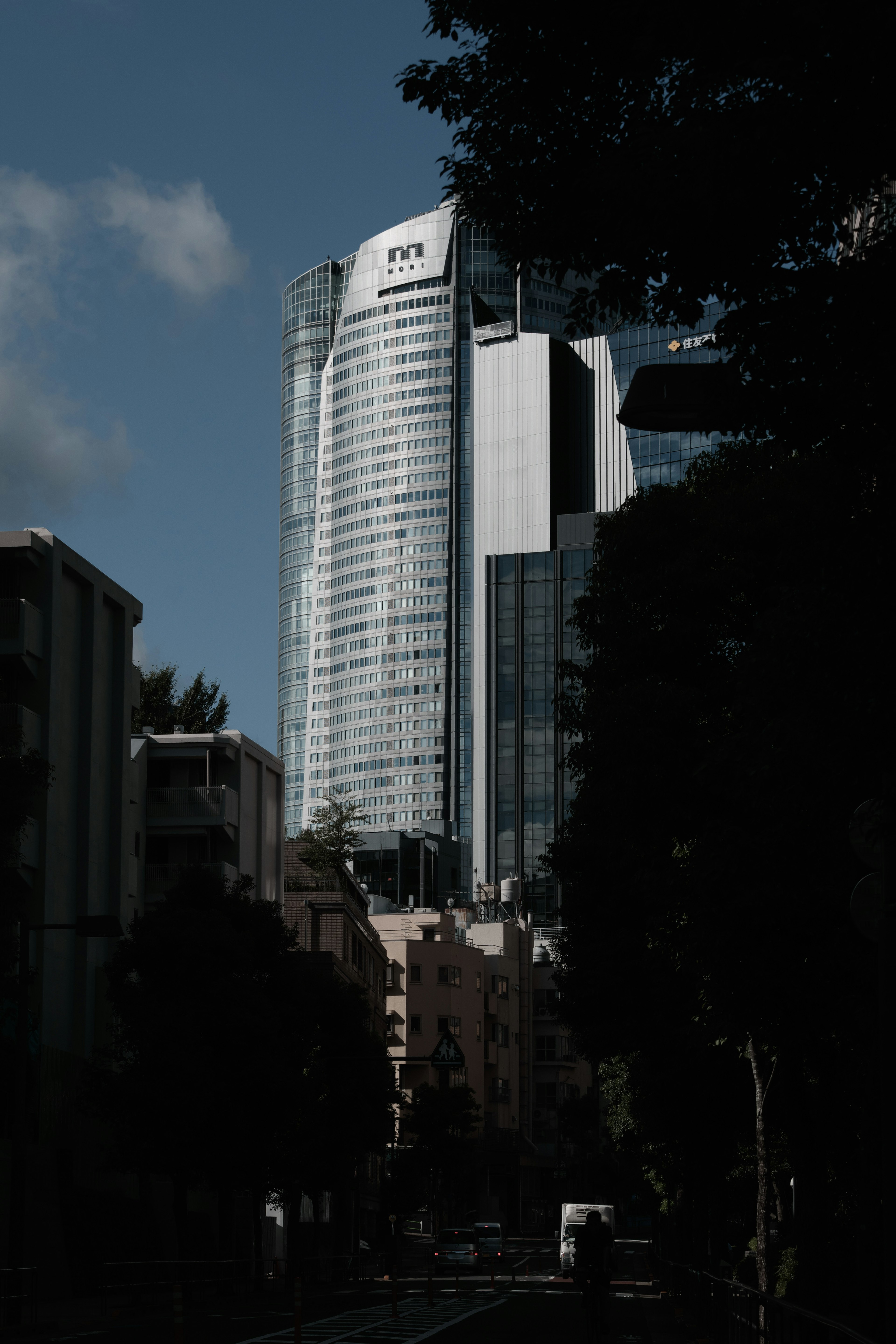 Bâtiment haut avec verre réfléchissant entouré d'arbres