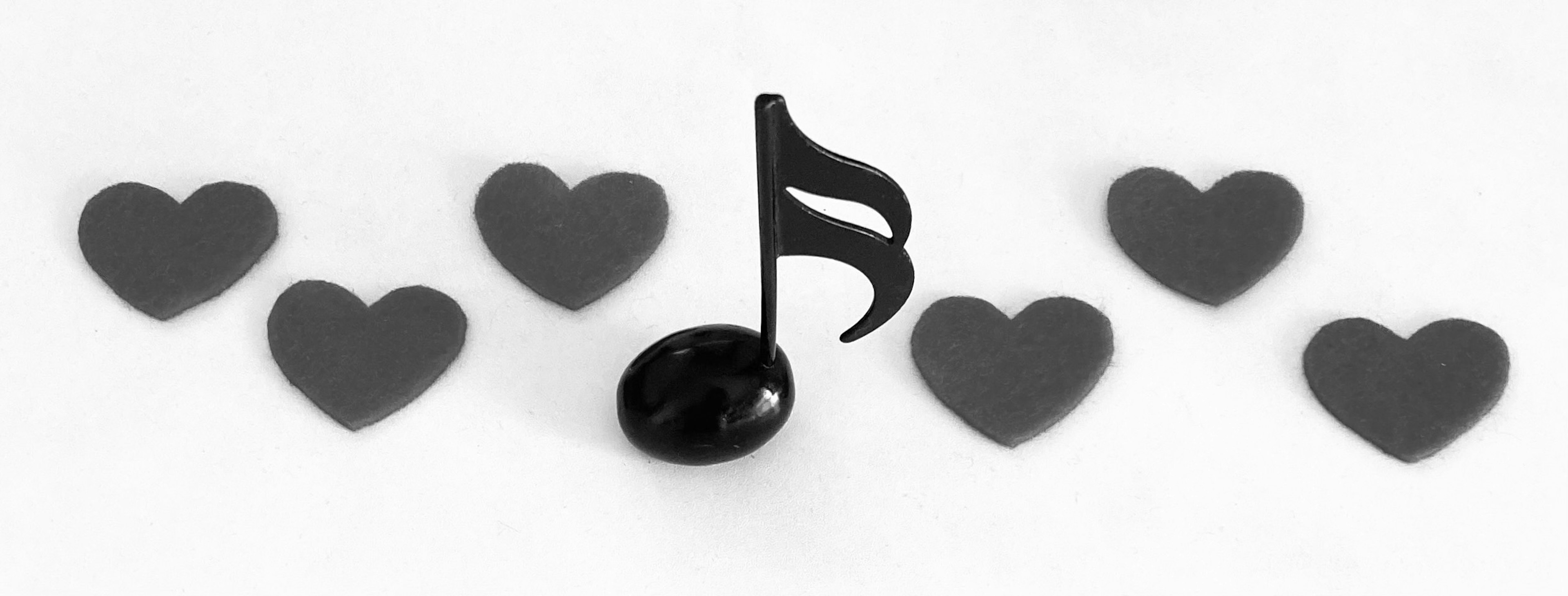 Black musical note surrounded by heart shapes in a monochrome design