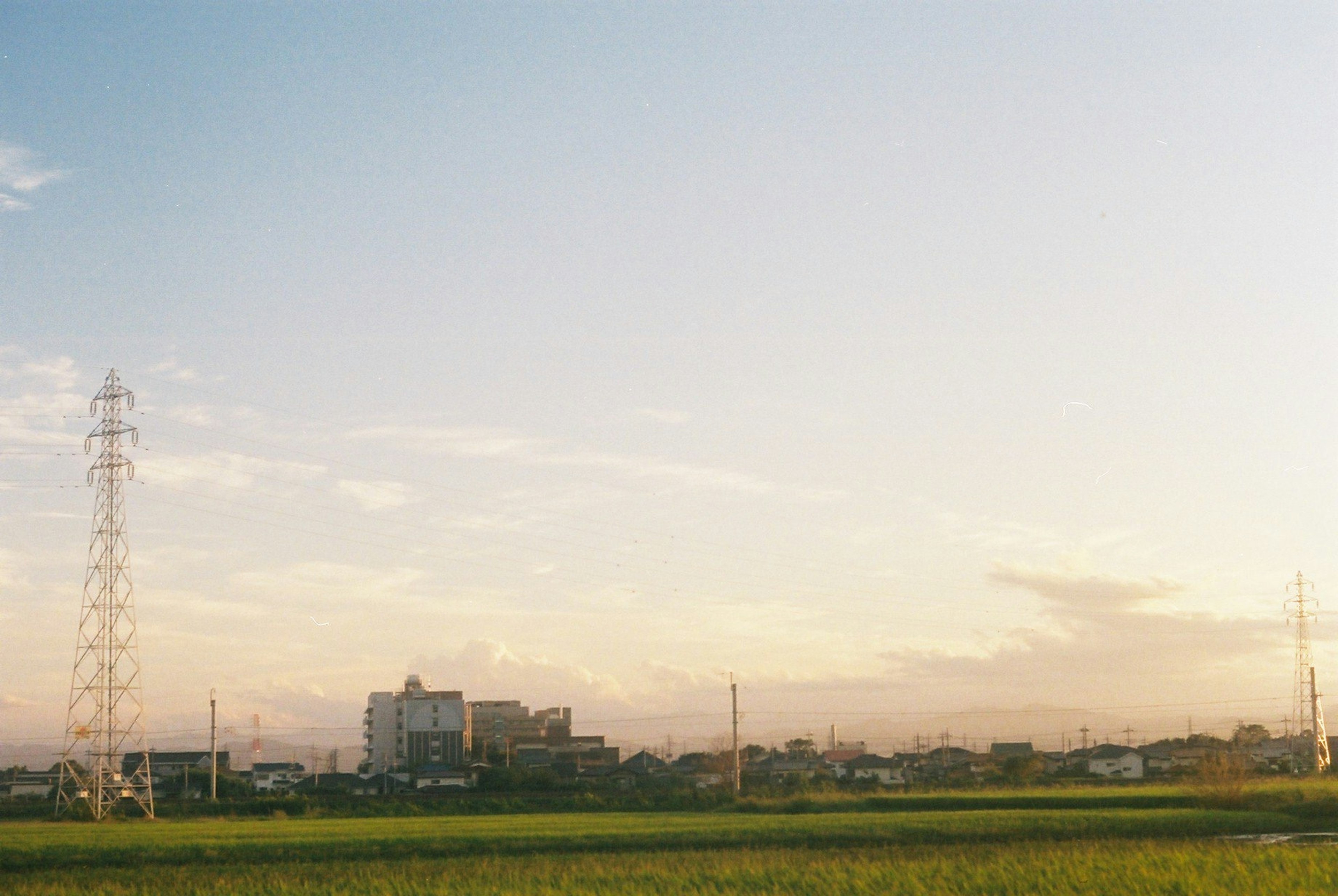 Vista al atardecer de campos con edificios al fondo