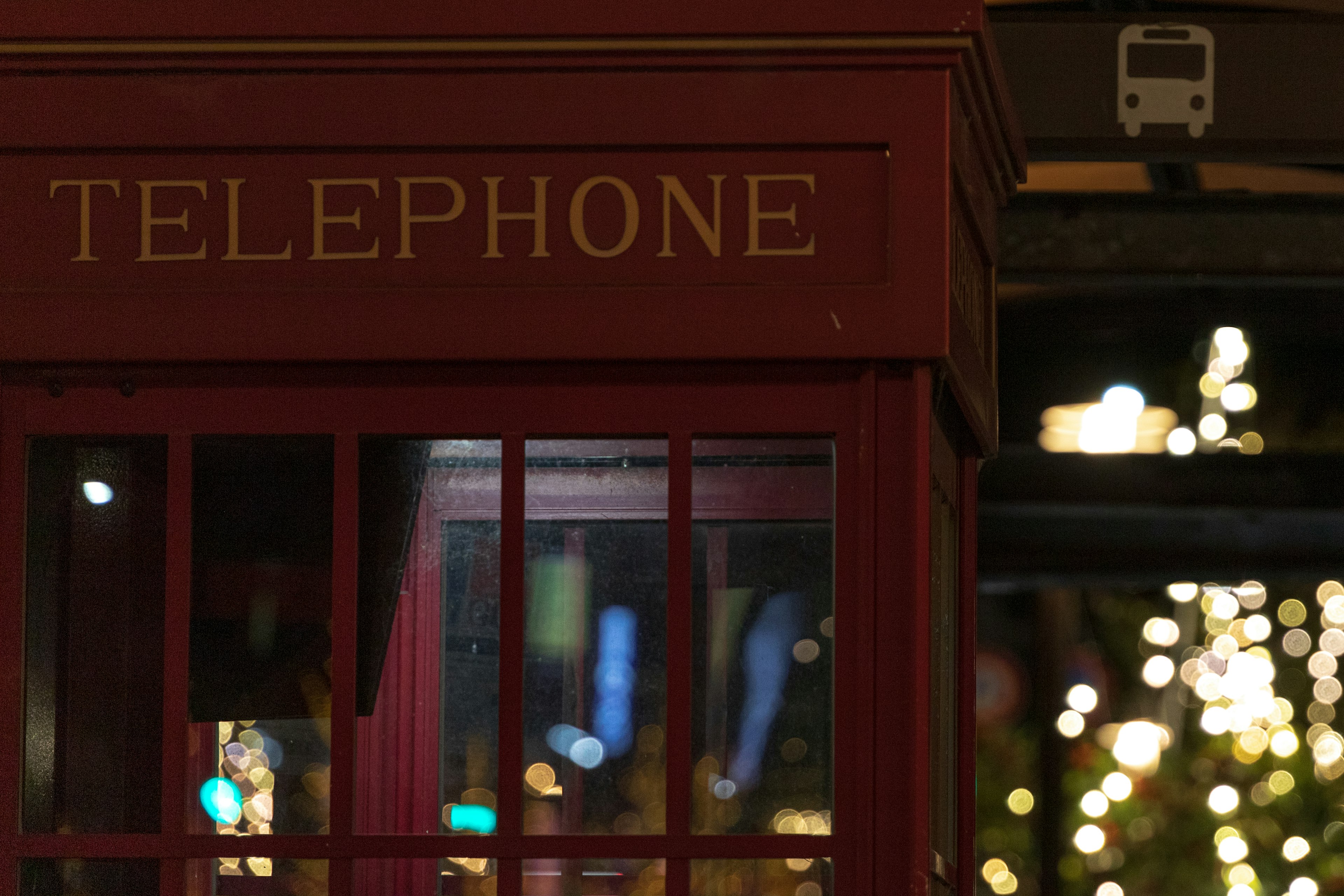 Red telephone booth with nighttime lights in the background