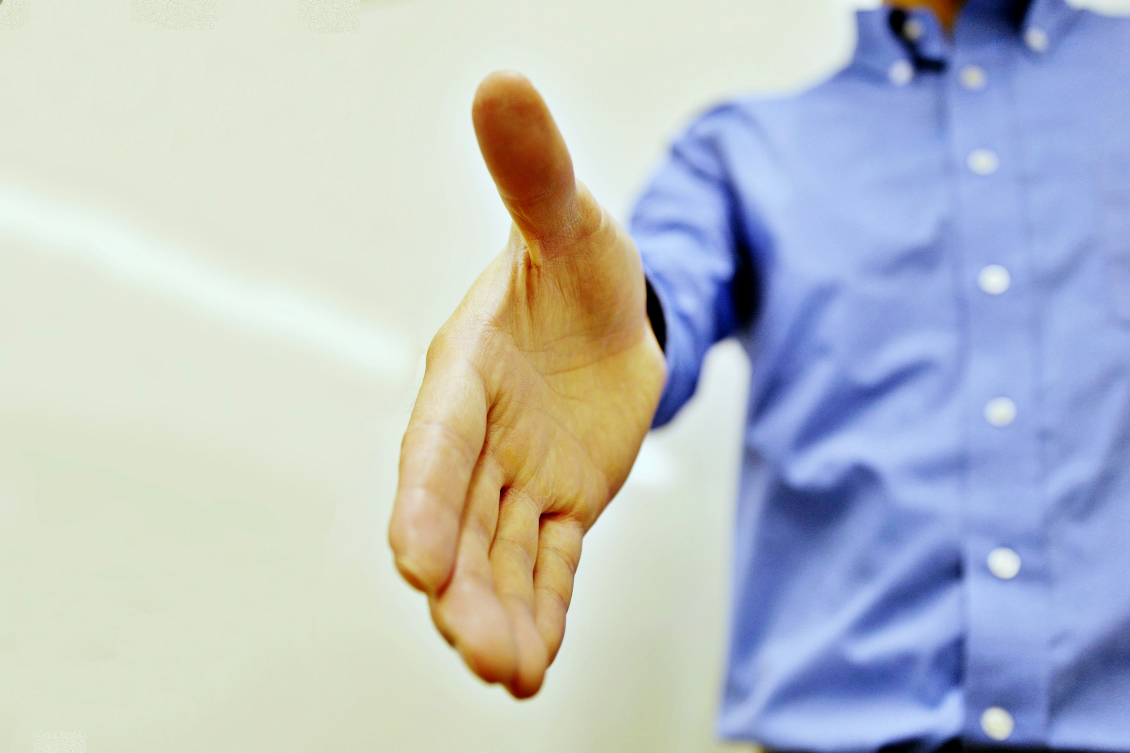 Image of a man extending his hand wearing a blue shirt