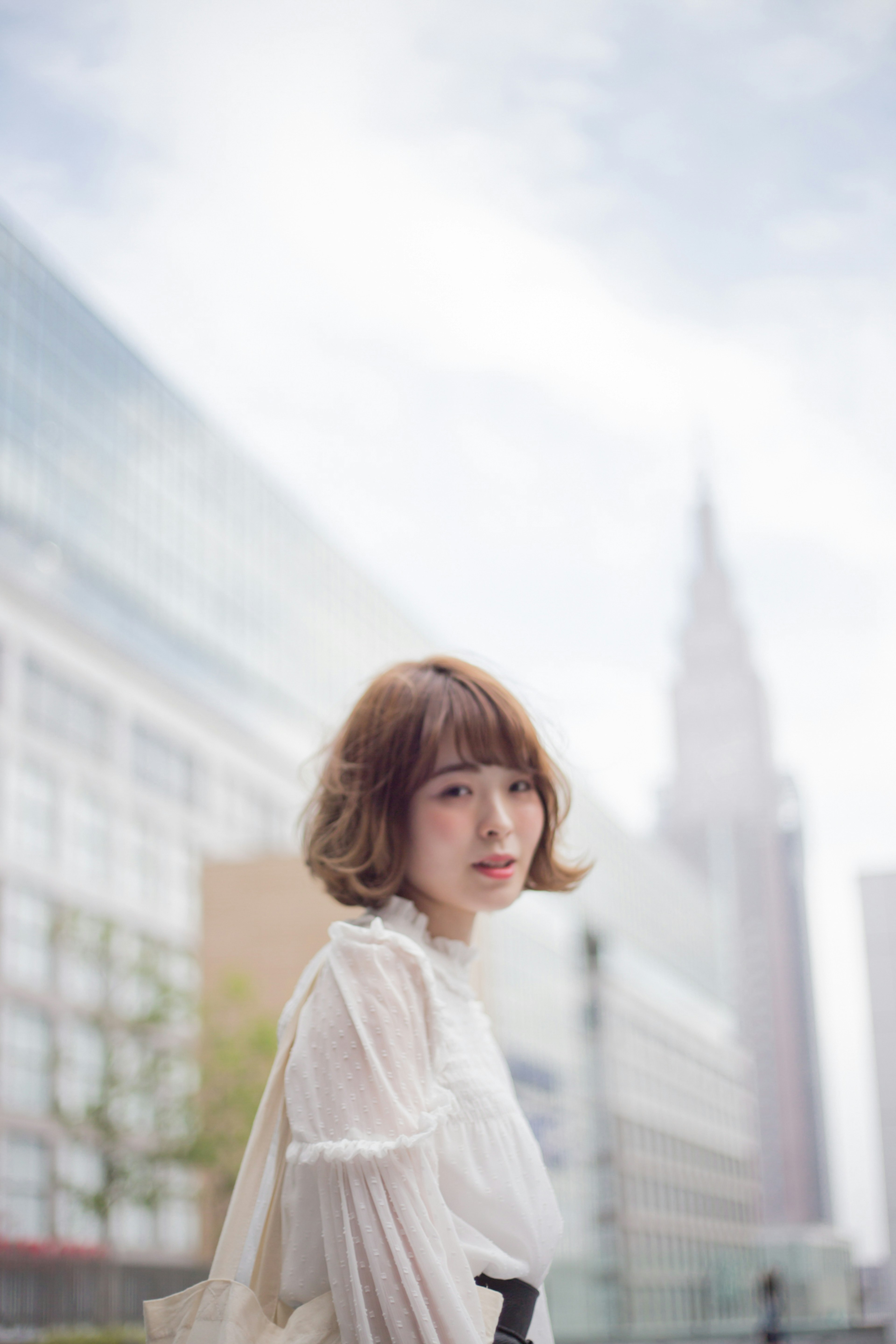 Portrait of a woman in a white blouse against an urban background